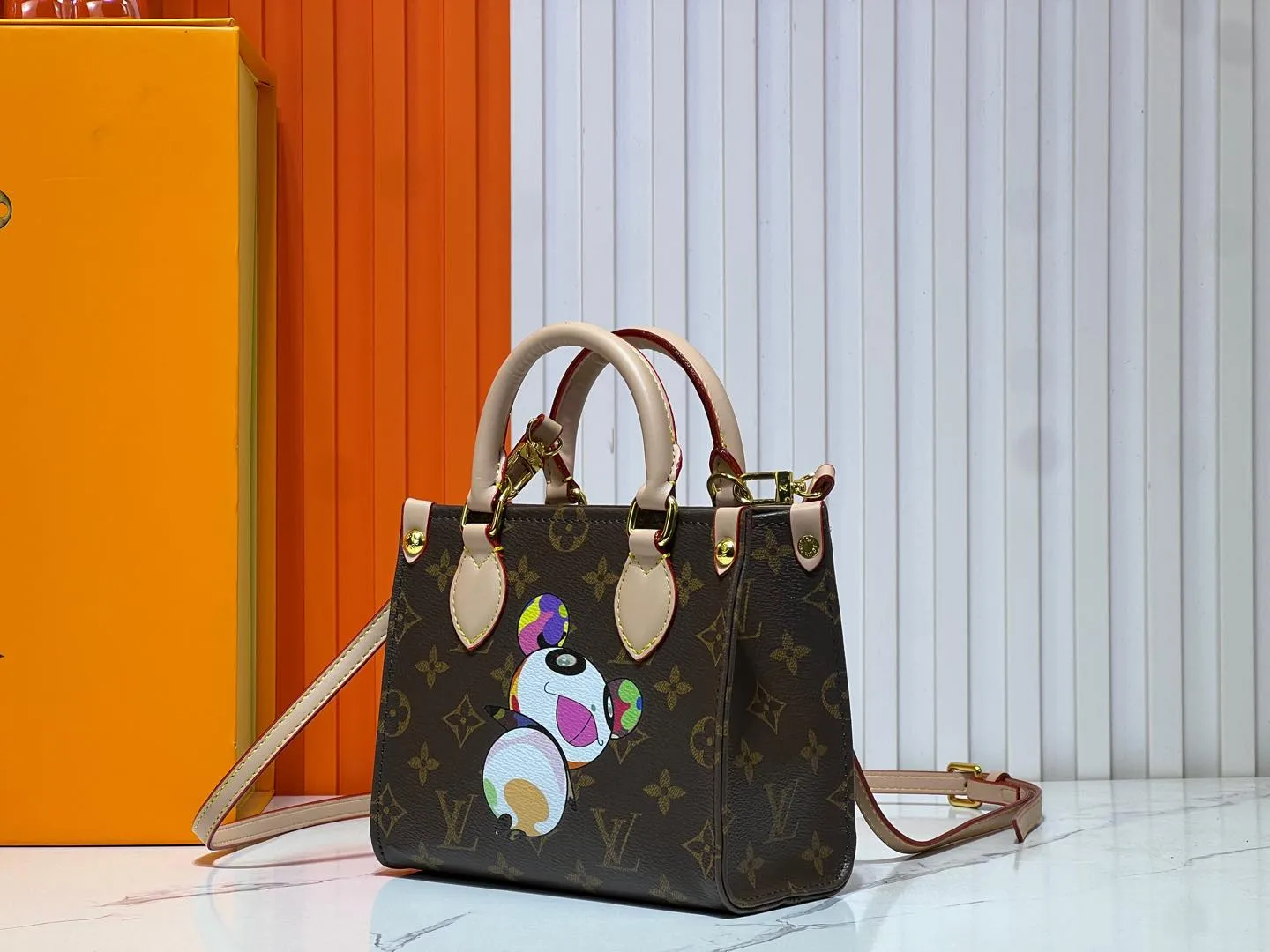 Batch 260💰M46993 M13668!🔥Lv&Takashi Murakami🐼Panda print OnTheGo BB new version The legendary ONTHEGO handbag: always able to meet your various needs for handbags. It has a large capacity but is not bulky. It is stiff and soft to the touch, making it suitable for home and travel. Tighten the side ties and it instantly transforms into a stylish urban handbag. Loosen the straps and it transforms into a chic and practical handbag. The slender leather handle can be carried over the shoulder or between the arms. The model shown here is made of Damier Azur canvas. Size: 18x15x8.5cm
