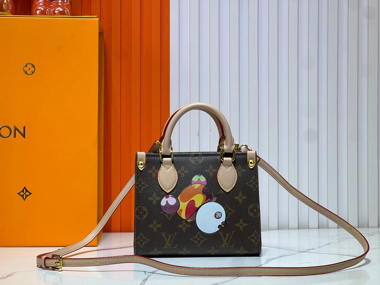 Batch 260💰M46993 M13668!🔥Lv&Takashi Murakami🐼Panda print OnTheGo BB new version The legendary ONTHEGO handbag: always able to meet your various needs for handbags. It has a large capacity but is not bulky. It is stiff and soft to the touch, making it suitable for home and travel. Tighten the side ties and it instantly transforms into a stylish urban handbag. Loosen the straps and it transforms into a chic and practical handbag. The slender leather handle can be carried over the shoulder or between the arms. The model shown here is made of Damier Azur canvas. Size: 18x15x8.5cm