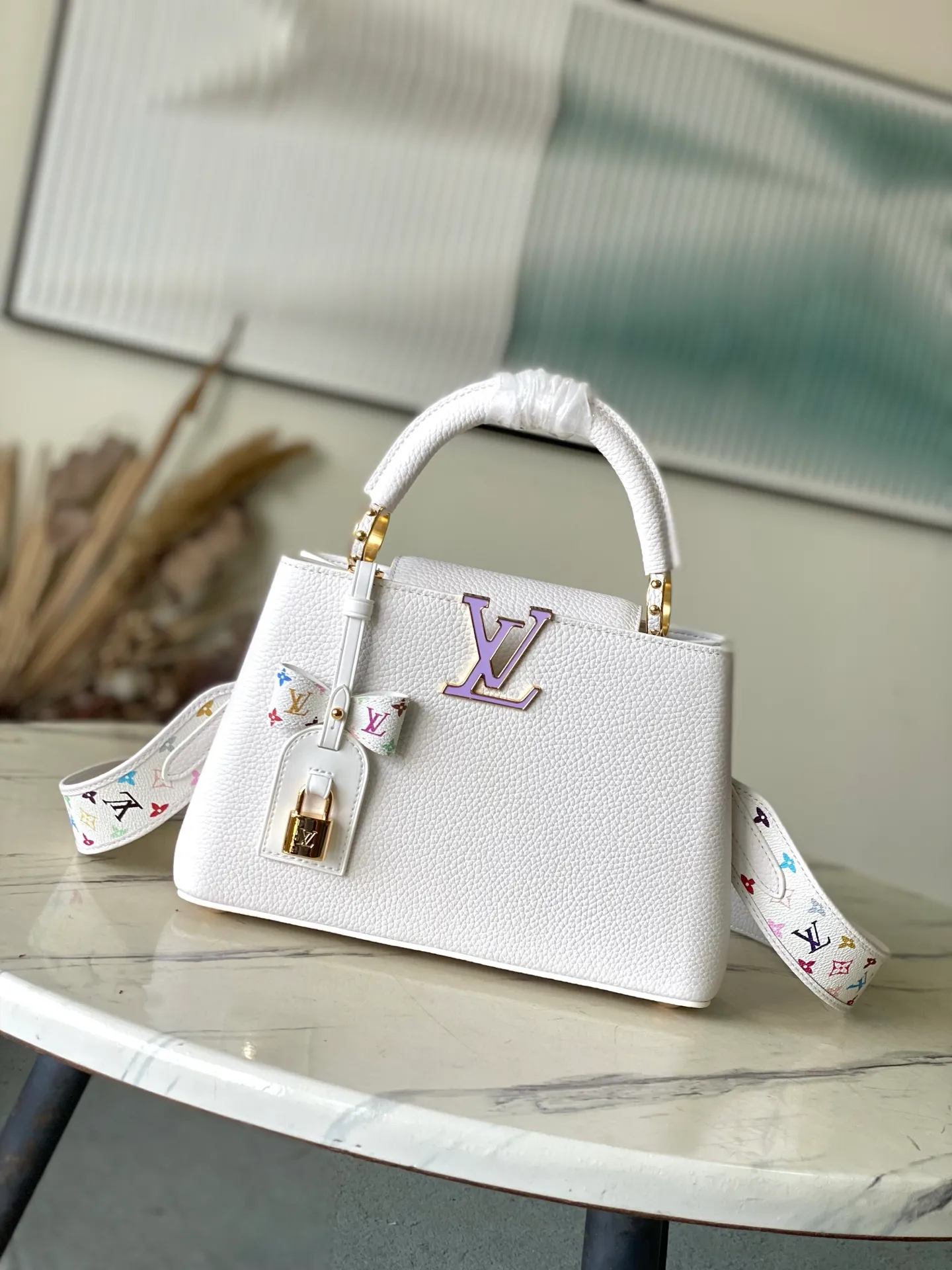 💰2360 "Special Original Leather" M13253 Small Size This Capucines handbag is from the Louis Vuitton x Murakami reissue series, using Taurillon cow leather to interpret the classic design. The LV letters and detachable Monogram strap are dipped in bright hues, a nod to the artist’s signature iridescent brushwork. The bow-shaped key holder and padlock decoration add sophisticated details, and the interior compartments and multiple pockets can easily store your daily needs. Dimensions: 27 × 17.3 × 9 cm