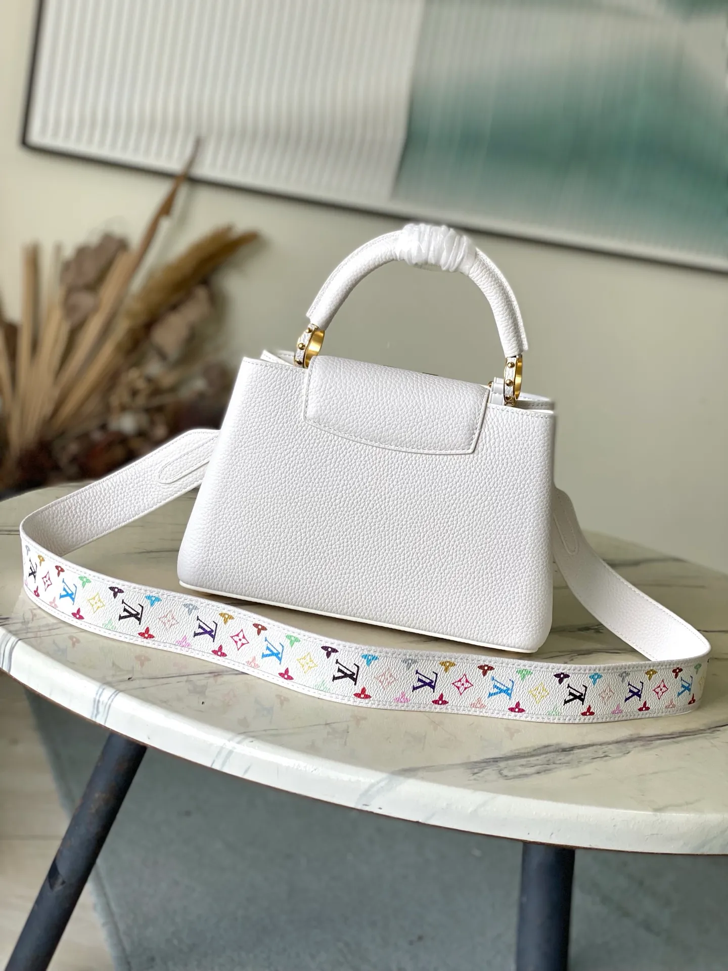 💰2360 "Special Original Leather" M13253 Small Size This Capucines handbag is from the Louis Vuitton x Murakami reissue series, using Taurillon cow leather to interpret the classic design. The LV letters and detachable Monogram strap are dipped in bright hues, a nod to the artist’s signature iridescent brushwork. The bow-shaped key holder and padlock decoration add sophisticated details, and the interior compartments and multiple pockets can easily store your daily needs. Dimensions: 27 × 17.3 × 9 cm