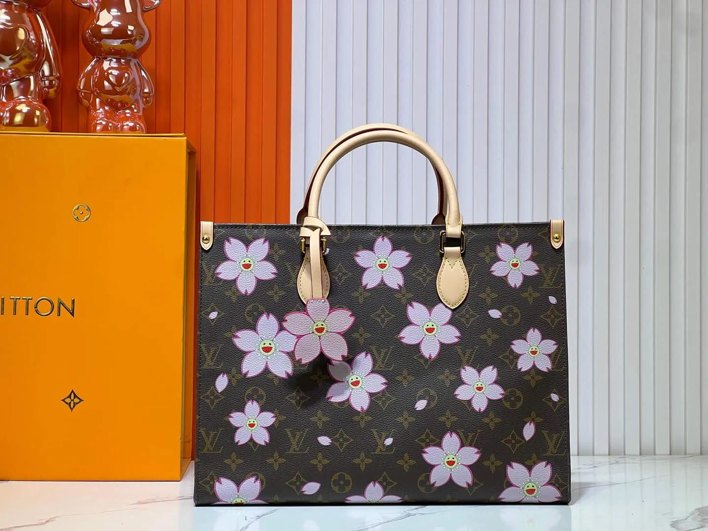 Batch 280💰M45039 M13668!🔥Lv&Takashi Murakami Sakura🌸OnTheGo new version The legendary ONTHEGO handbag: always able to meet your various needs for handbags. It has a large capacity but is not bulky. It is stiff and soft to the touch, making it suitable for home and travel. Tighten the side ties and it instantly transforms into a stylish urban handbag. Loosen the straps and it transforms into a chic and practical handbag. The slender leather handle can be carried over the shoulder or between the arms. The model shown here is made of Damier Azur canvas. Size: 35x27x14cm