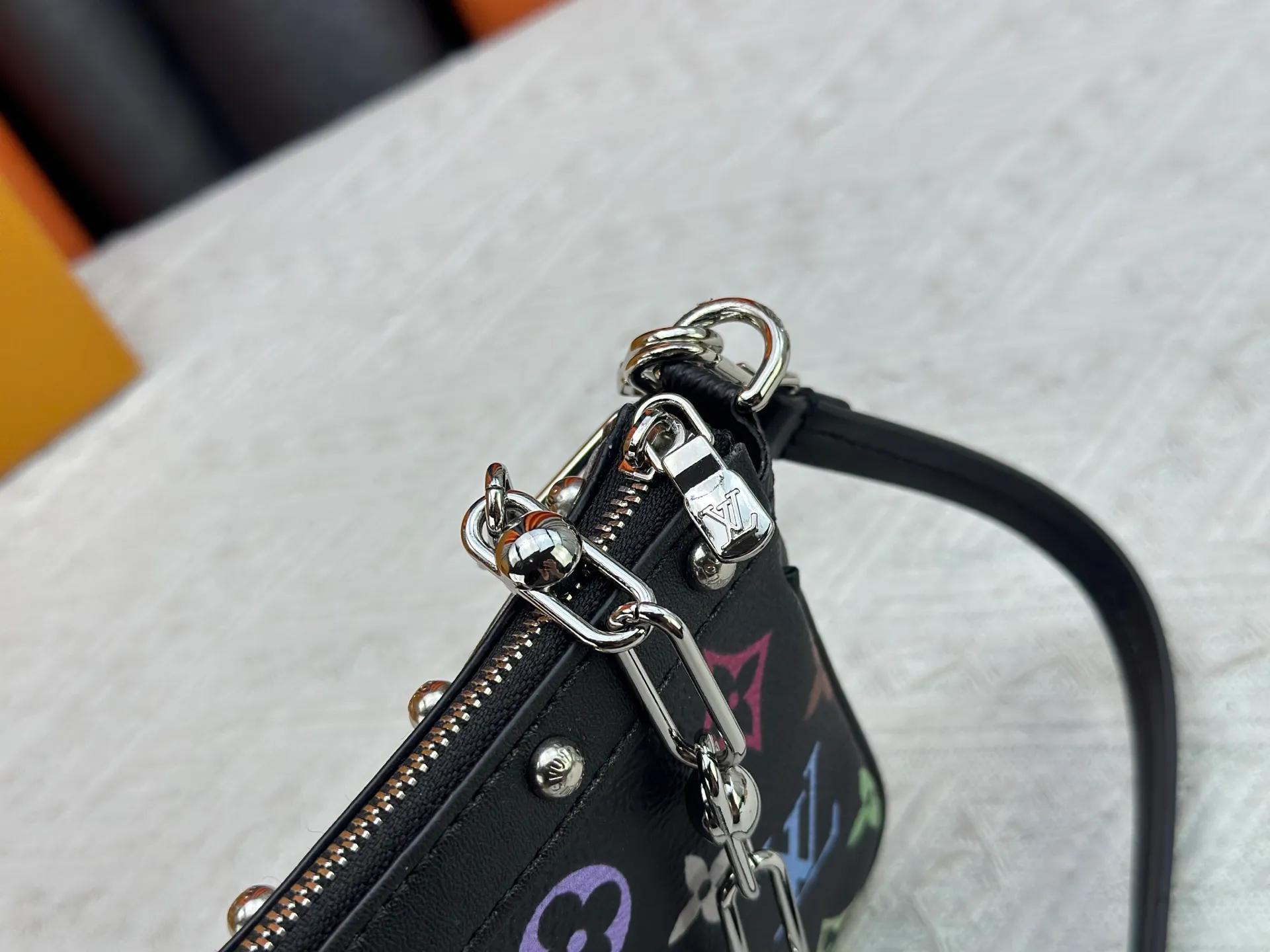 P220 M13404 M13663 Black color White color This Pochette Accessoires handbag is made of coated canvas, with colorful Monogram patterns to interpret the smart style of the Louis Vuitton × Murakami cross-border collaboration series. Calf leather trim and dazzling hardware add to the sophisticated details, while the detachable shoulder strap and chain provide flexible carry. Size: 22x13x4cm