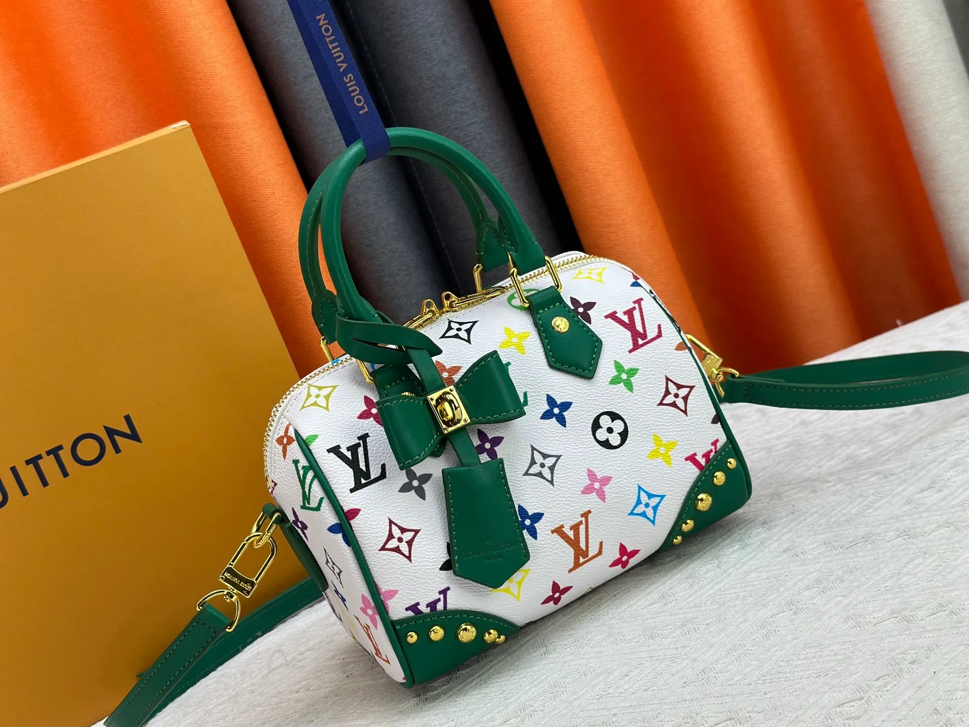 P260 upgraded original M58953 M46234 M46222 Speedy Bandoulière 20 handbag is made of soft coated canvas, and the full-length Monogram pattern is traced in colorful rainbow tones, highlighting the smart style of the Louis Vuitton x Murakami reissue series. The Toron handle and detachable shoulder strap are constructed of cow leather, the metal corners recall classic luggage elements, and the bow-shaped key bag and padlock add brand touches. Dimensions: 20.5 x 13.5 x 12.0 cm (length x height x width)