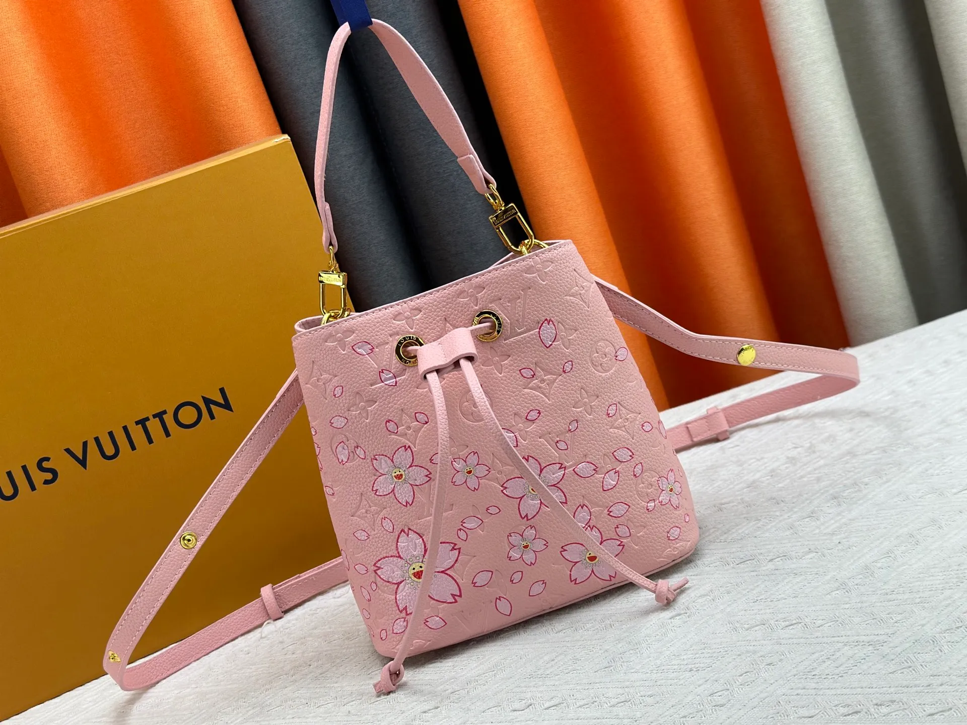 P240 M13676 M44021 This NeoNoe BB bucket bag comes from the Louis Vuitton × Murakami replica series, using Monogram Empreinte leather to convey a fresh breath and smart style. Murakami's signature Cherry Blossom pattern appears on the Monogram embossed surface, and the same floral element is transformed into a slide buckle to tighten the drawstring. Size: 20x20x13cm