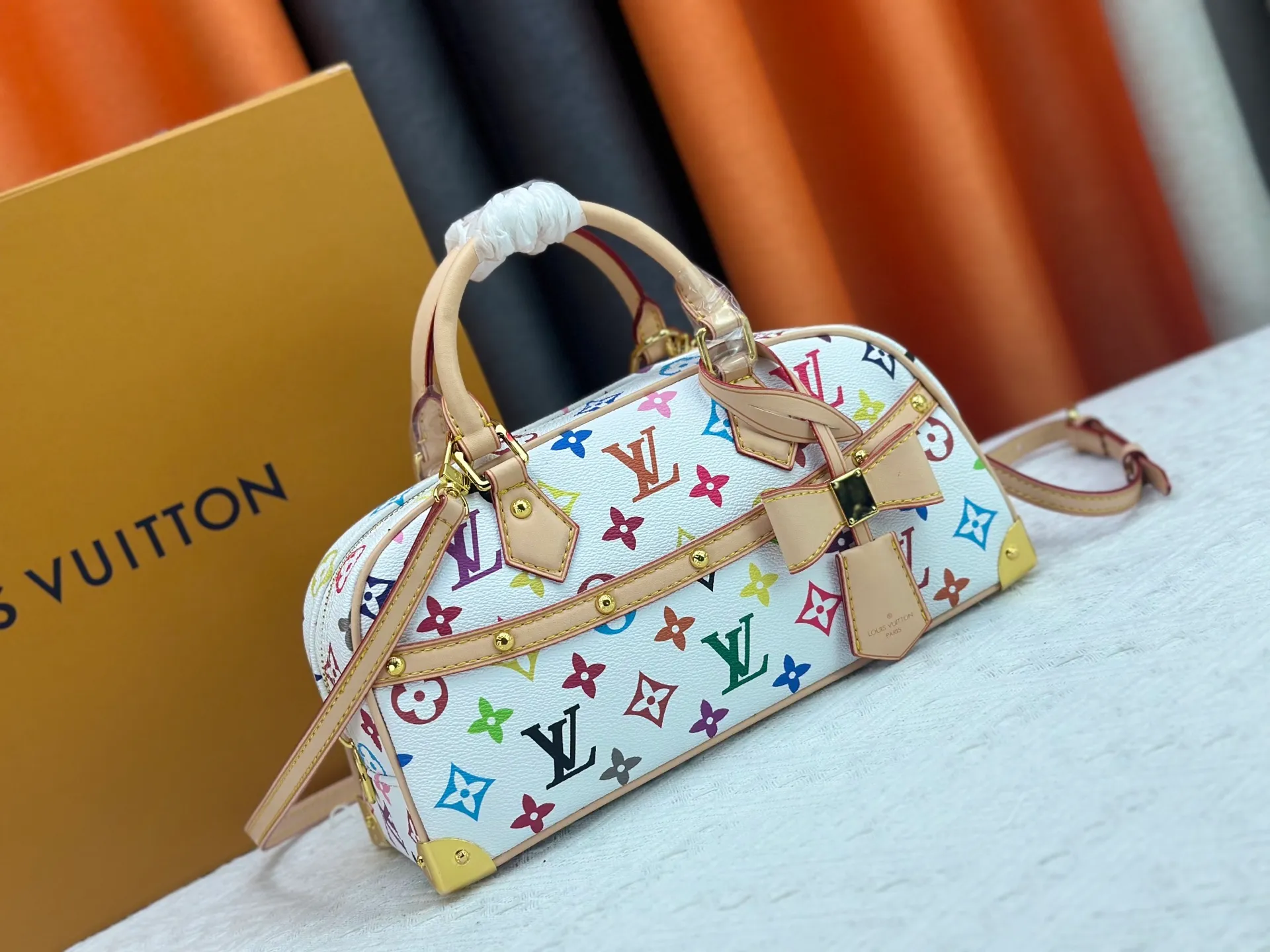 P280 Upgraded Original M13084 This Handbag East West handbag is from the Louis Vuitton x Takashi Murakami reissue series, using the artist's signature rainbow tones to trace the full-length Monogram pattern. Sleek horizontal construction lines the top handle, studded side straps, detachable and adjustable shoulder strap and LV x TM key holder, with cowhide leather details and sophisticated corners that nod to the brand's traditional luggage. Dimensions: 27.0 x 14.0 x 10.0 cm (length x height x width)