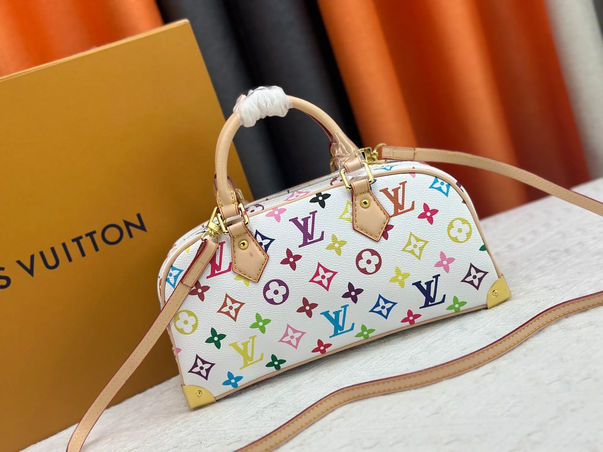 P280 Upgraded Original M13084 This Handbag East West handbag is from the Louis Vuitton x Takashi Murakami reissue series, using the artist's signature rainbow tones to trace the full-length Monogram pattern. Sleek horizontal construction lines the top handle, studded side straps, detachable and adjustable shoulder strap and LV x TM key holder, with cowhide leather details and sophisticated corners that nod to the brand's traditional luggage. Dimensions: 27.0 x 14.0 x 10.0 cm (length x height x width)