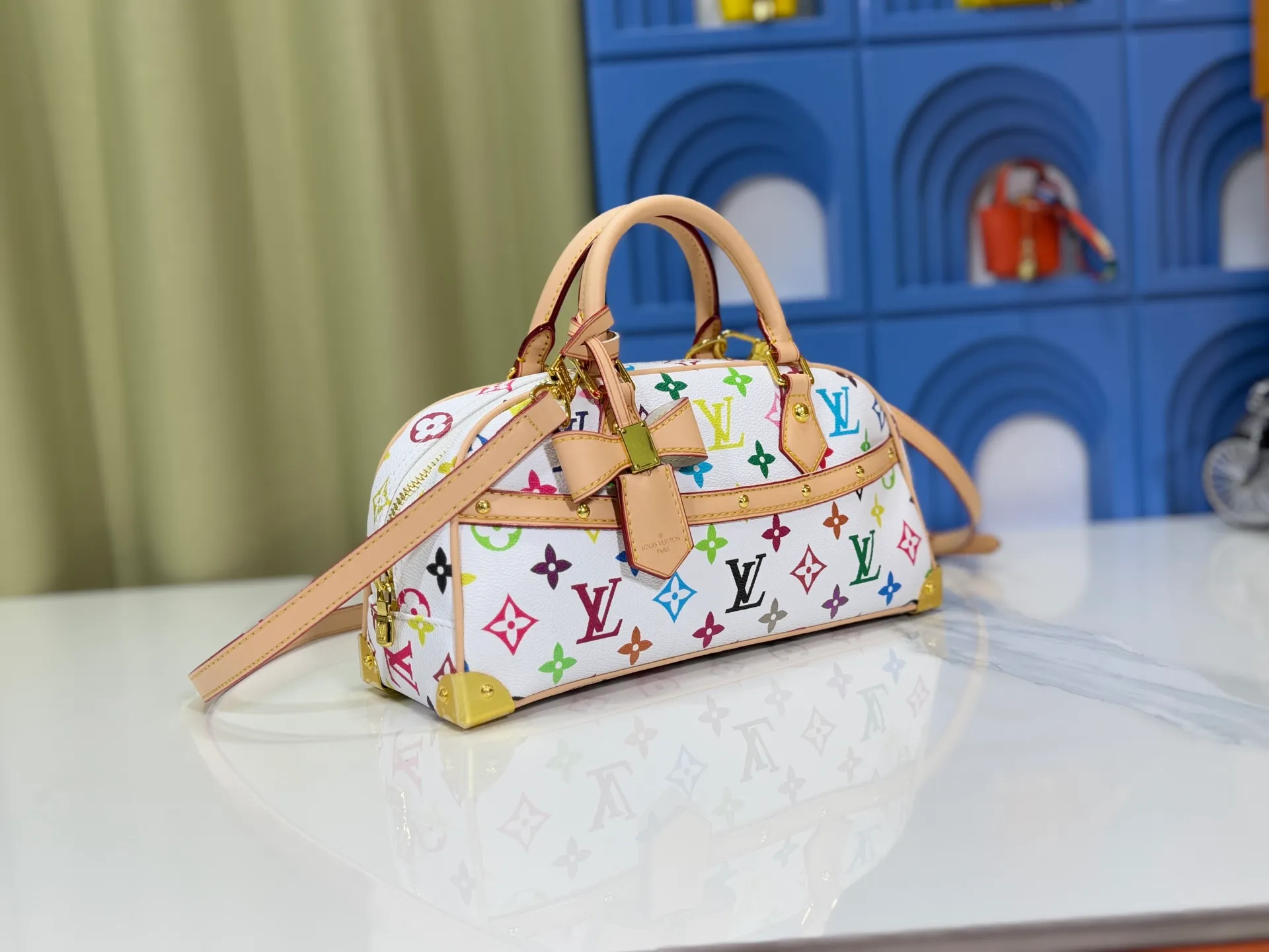 P300 Upgraded Original M13084 This Handbag East West handbag is from the Louis Vuitton x Takashi Murakami reissue series, using the artist's signature rainbow tones to trace the full-length Monogram pattern. Sleek horizontal construction lines the top handle, studded side straps, detachable and adjustable shoulder strap and LV x TM key holder, with cowhide leather details and sophisticated corners that nod to the brand's traditional luggage. Dimensions: 27.0 x 14.0 x 10.0 cm (length x height x width)