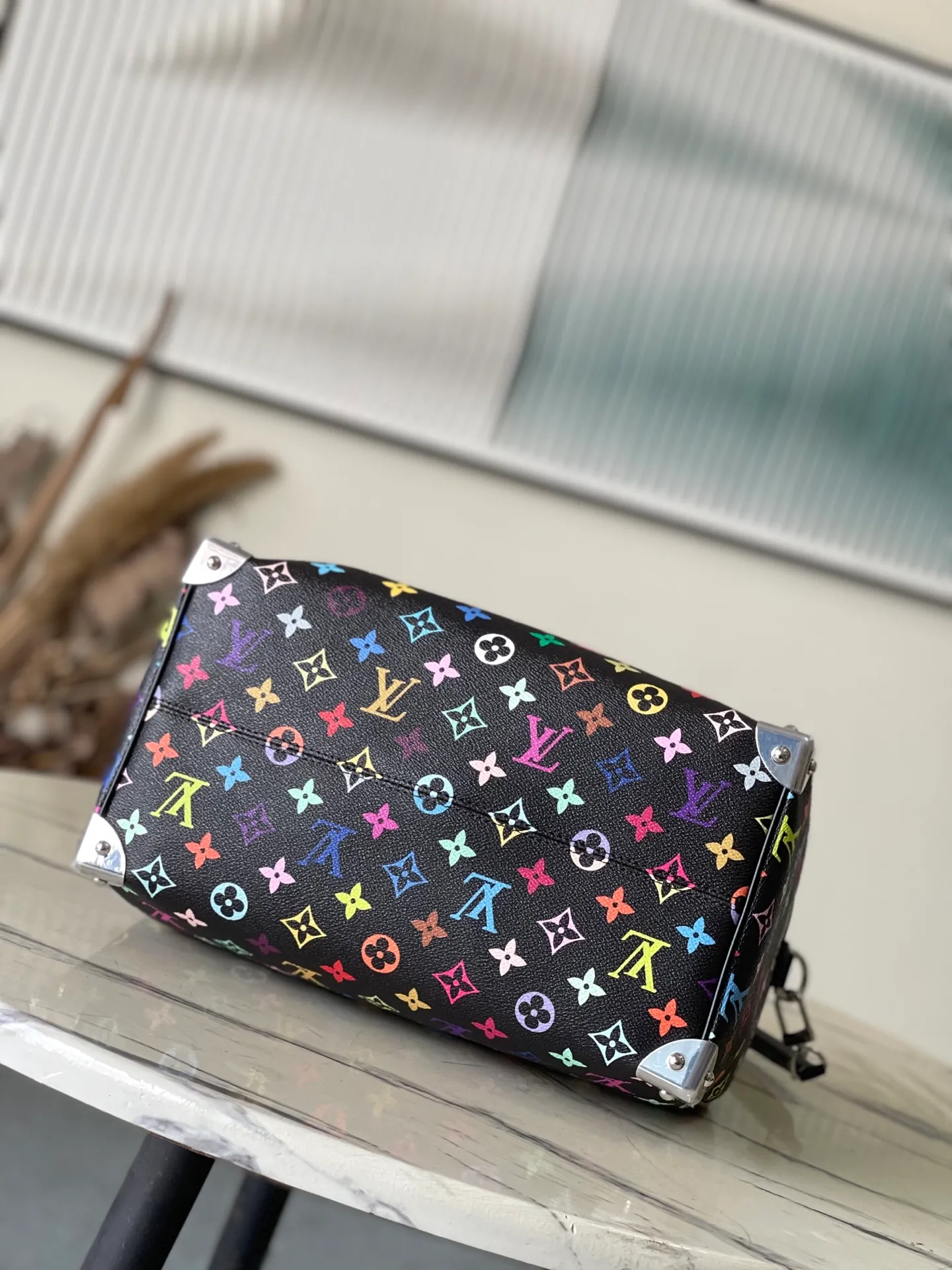 💰1180 Top Original M13257 This SpeedySoft 30 handbag is made of soft coated canvas, and the full-length Monogram pattern is traced in colorful rainbow tones, highlighting the smart style of the x Murakami Takashi reissue series. The Toron handle and detachable shoulder strap are constructed of cow leather, the metal corners recall classic luggage elements, and the bow-shaped key bag and padlock add brand touches. Dimensions: 30 × 21 × 17 cm