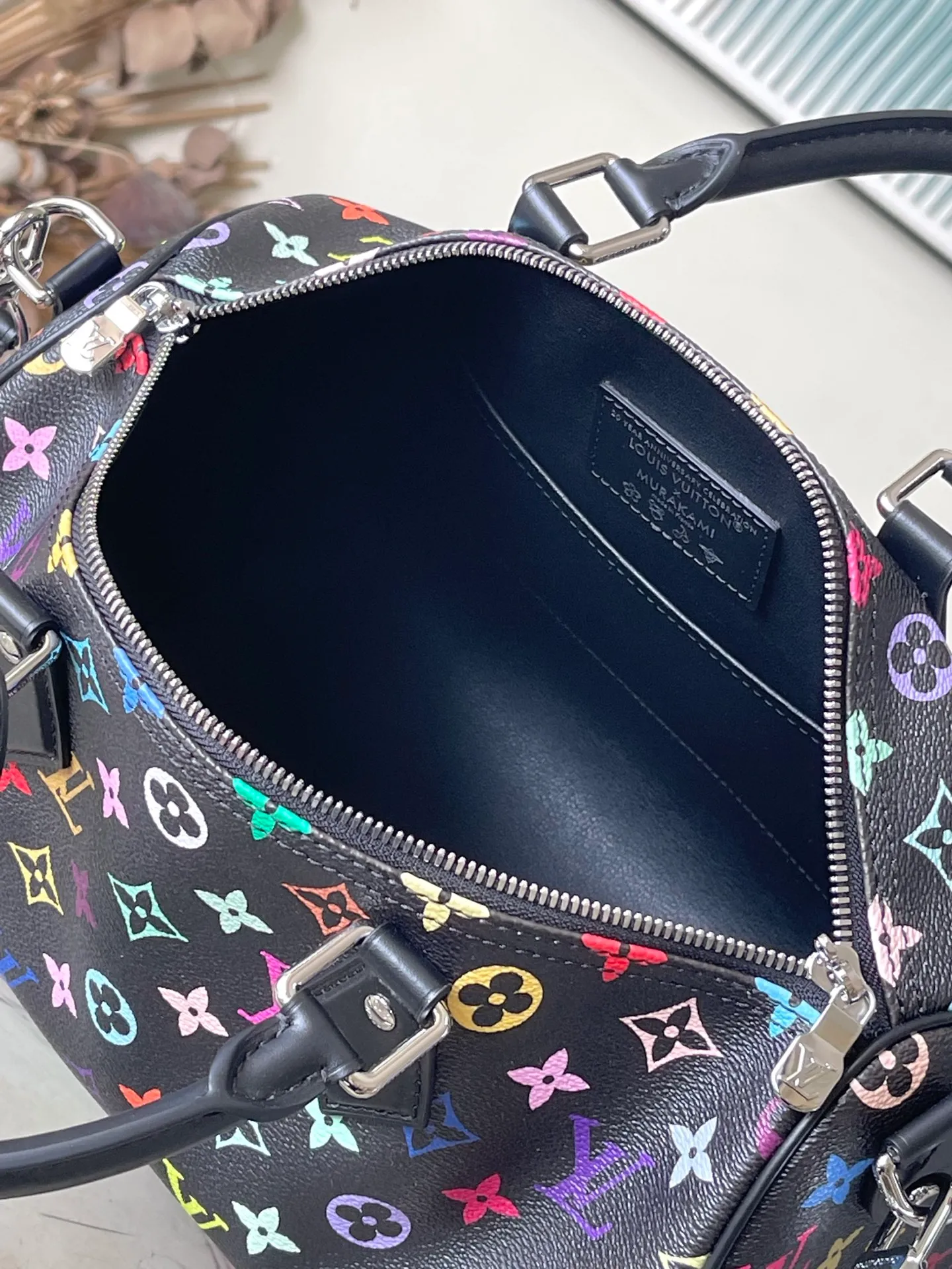 💰1180 Top Original M13257 This SpeedySoft 30 handbag is made of soft coated canvas, and the full-length Monogram pattern is traced in colorful rainbow tones, highlighting the smart style of the x Murakami Takashi reissue series. The Toron handle and detachable shoulder strap are constructed of cow leather, the metal corners recall classic luggage elements, and the bow-shaped key bag and padlock add brand touches. Dimensions: 30 × 21 × 17 cm