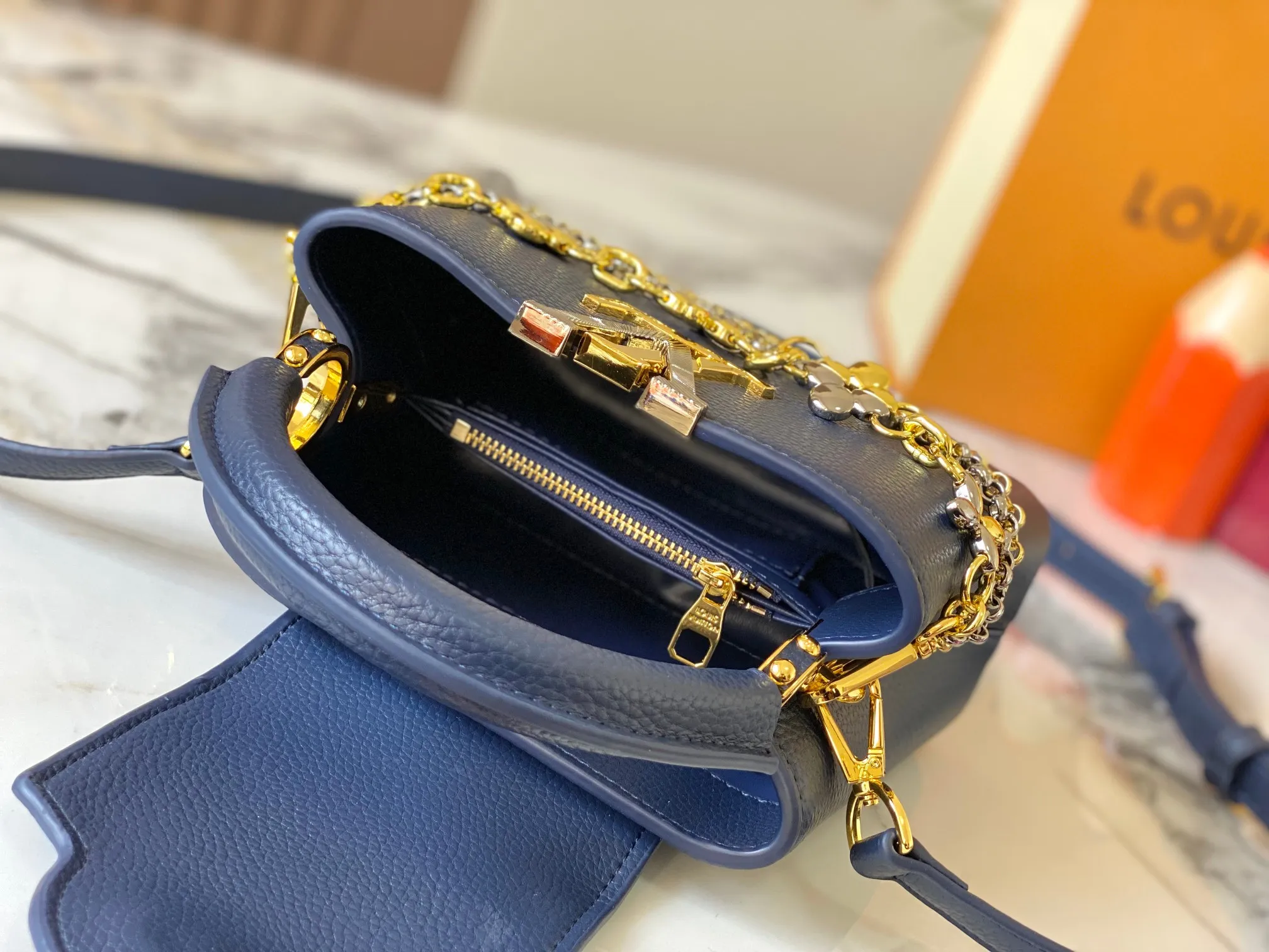 P480 [Guangzhou top quality original version] M26351 Blue This modern version of the Capucines mini is made of timeless Taurillon leather and equipped with a jewelry-inspired Infinity chain. The bag is decorated with double galvanized metal parts, including the iconic Monogram floral pattern, and the LV Initials logo created with sunburst technology, creating a sundial-like light and shadow effect. The bag has multiple pockets and a detachable shoulder strap, allowing it to be carried on one shoulder or across the body. 14 x 8 x 21 cm (height x width x length)