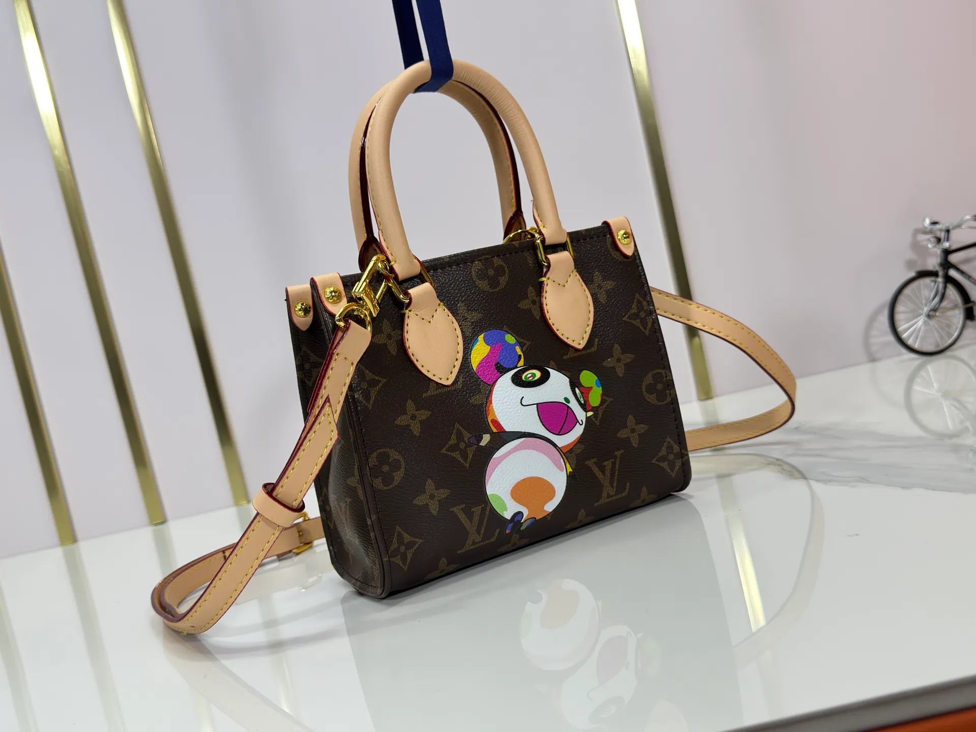 P220 upgraded original M13668 M46839 Louis Vuitton x Murakami reissue series interprets the exquisite version of the OnTheGo handbag with playful touches. Monogram canvas and cow leather establish the brand's classic style, and Murakami's cute and cute panda image is transformed into front and back prints. The detachable and adjustable shoulder strap provides a variety of carrying options, and the zippered interior pocket keeps personal items safe and secure. Dimensions: 18.0 x 15.0 x 8.5 cm (length x height x width)