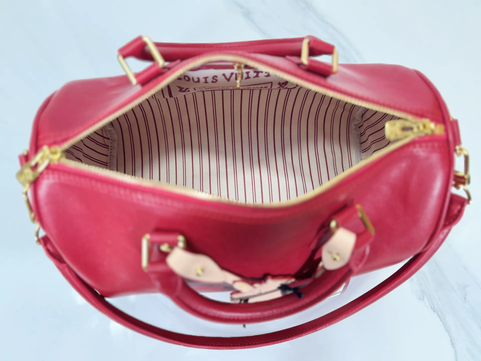 P260 M25766 M24424 M24425 Size: 30×21×17CM [SPEEDY SOFT 30 handbag] This Speedy Soft 30 is from the LV Travels With Grace Coddington series. It is made of rich-toned cow leather with metal parts and a fun cat-shaped key bag. Removable name tag features Grace Coddington's handwriting.