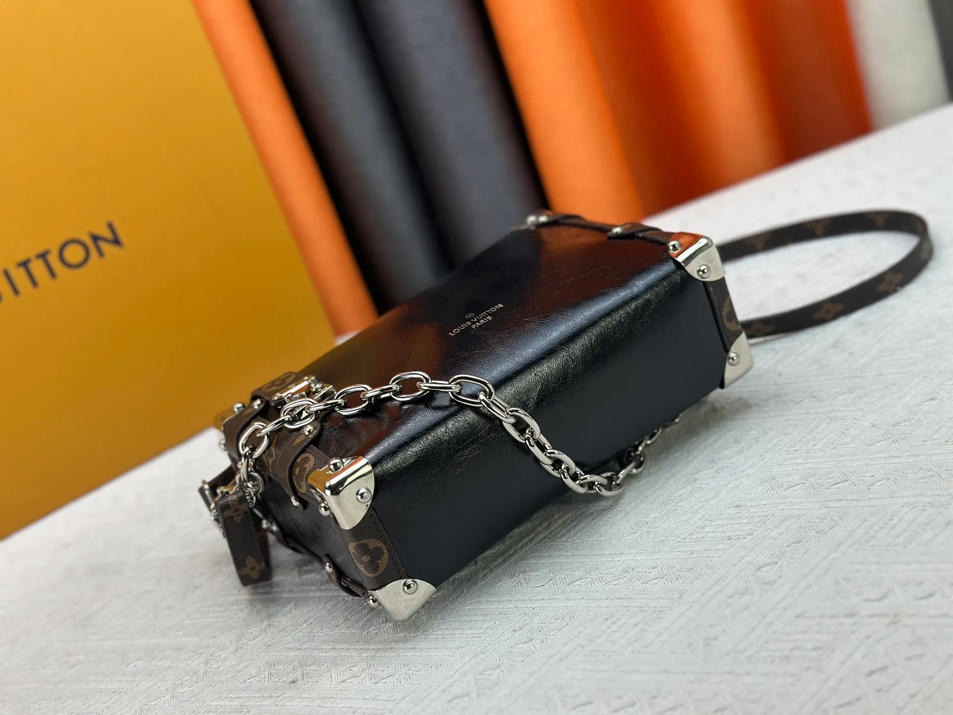 P300 M15195 M46358 This Side Trunk Vibe handbag reimagines the brand's classic Side Trunk silhouette with an avant-garde design, inspired by Louis Vuitton's traditional travel trunks. Crafted from smooth glossy Vibe textured cow leather, it features a leather-covered rivet frame and metal S-lock closure for a rock-and-roll style. Thanks to the multiple designs of the detachable chain, detachable leather handle and adjustable leather shoulder strap, it provides a variety of carrying options. Dimensions: 23.5x16x8.5cm