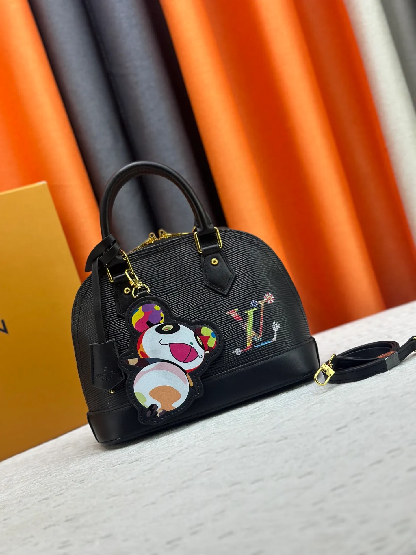 p300 Upgraded original M13670 M14197 M53152 This Alma BB handbag is made of Epi leather and appears in the Louis Vuitton x Murakami reissue series. The smart LV letters on the front reflect the Japanese artist's "ultra-flat" aesthetic, which contrasts with the removable distinctive panda decoration. Top handles, a removable shoulder strap and a dazzling padlock complete the Art Deco design. Dimensions: 23.5 x 17.5 x 11.5 cm (length x height x width)