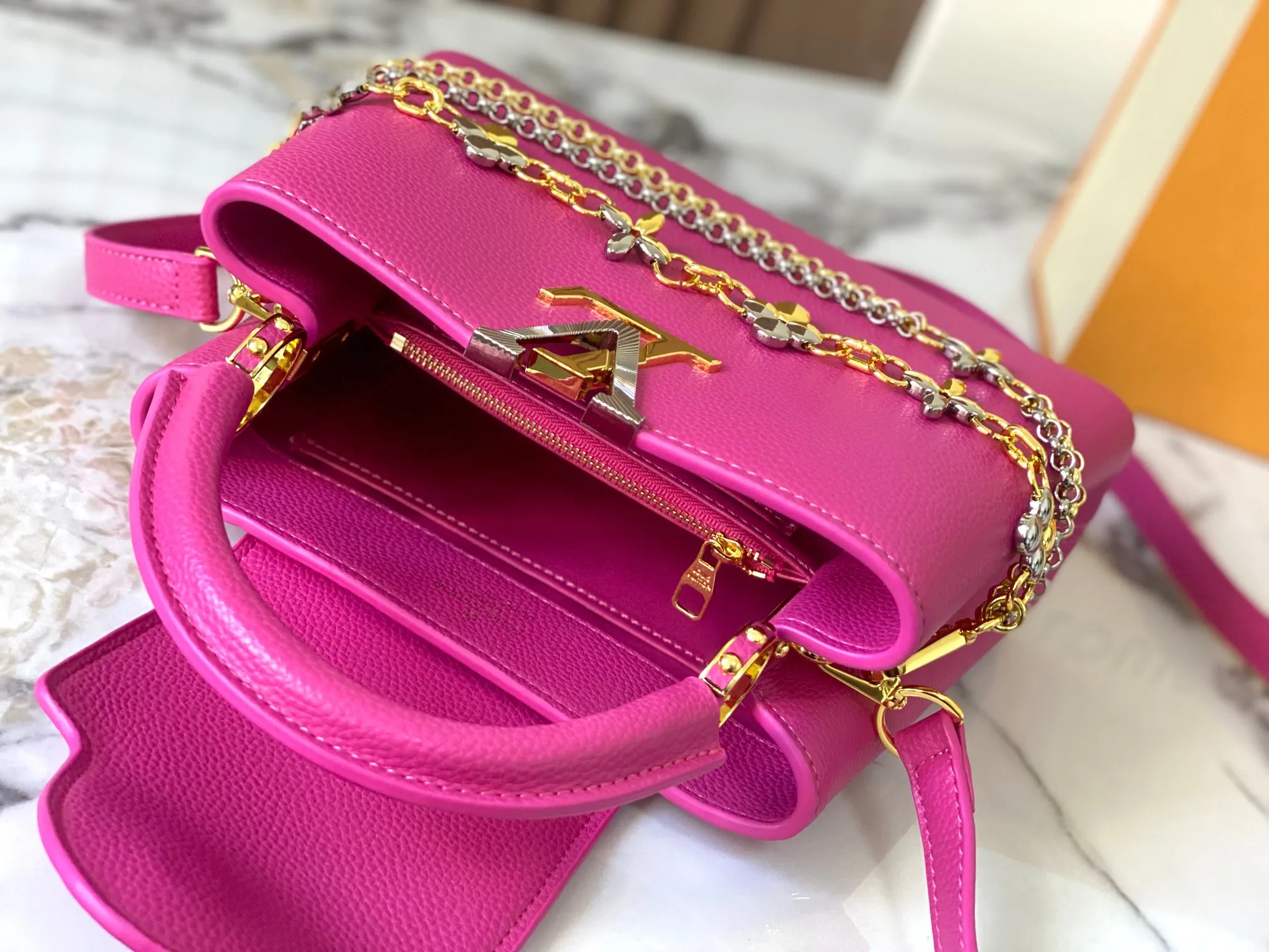 P500 [Guangzhou top quality original version] M26532 Rose Red This modern version of Capucines BB is made of timeless Taurillon leather and equipped with a jewelry-inspired Infinity chain. The bag is decorated with double galvanized metal parts, including the iconic Monogram floral pattern, and the LV Initials logo created with sunburst technology, creating a sundial-like light and shadow effect. The bag has multiple pockets and a detachable shoulder strap, allowing it to be carried on one shoulder or across the body. 27 x 17.3 x 9 (cm) (length x height x width)