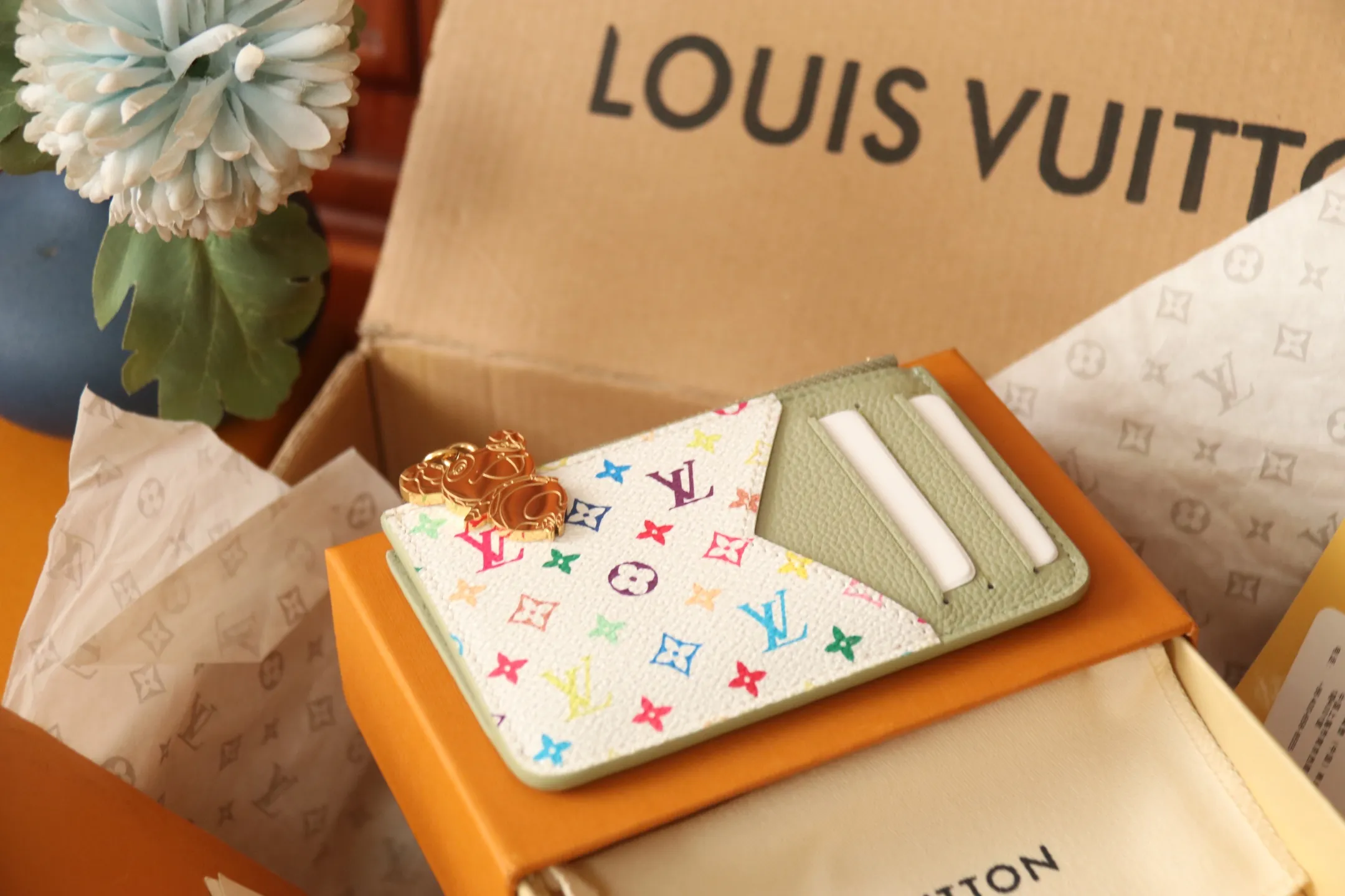 【LV x TM Romy Card Holder】 💎p400 m14155 rose m14171 blue m13800 green "LV × TM Porto Kurt Romy" appears in the "Louis Vuitton × Takashi Murakami" series that unfolds in a variety of categories. It features functional and playful expressions with fresh tones inspired by the rainbow colors unique to Japanese artists. The whole piece is finished with Monogram Amplant leather that adds a casual personality, and the bright Monogram multi-color canvas in the flat pocket stands out. The coin pocket opens and closes with a gold zipper and features a panda pull to symbolize the season.  Dimensions: 12 x 8 x 0.8 cm