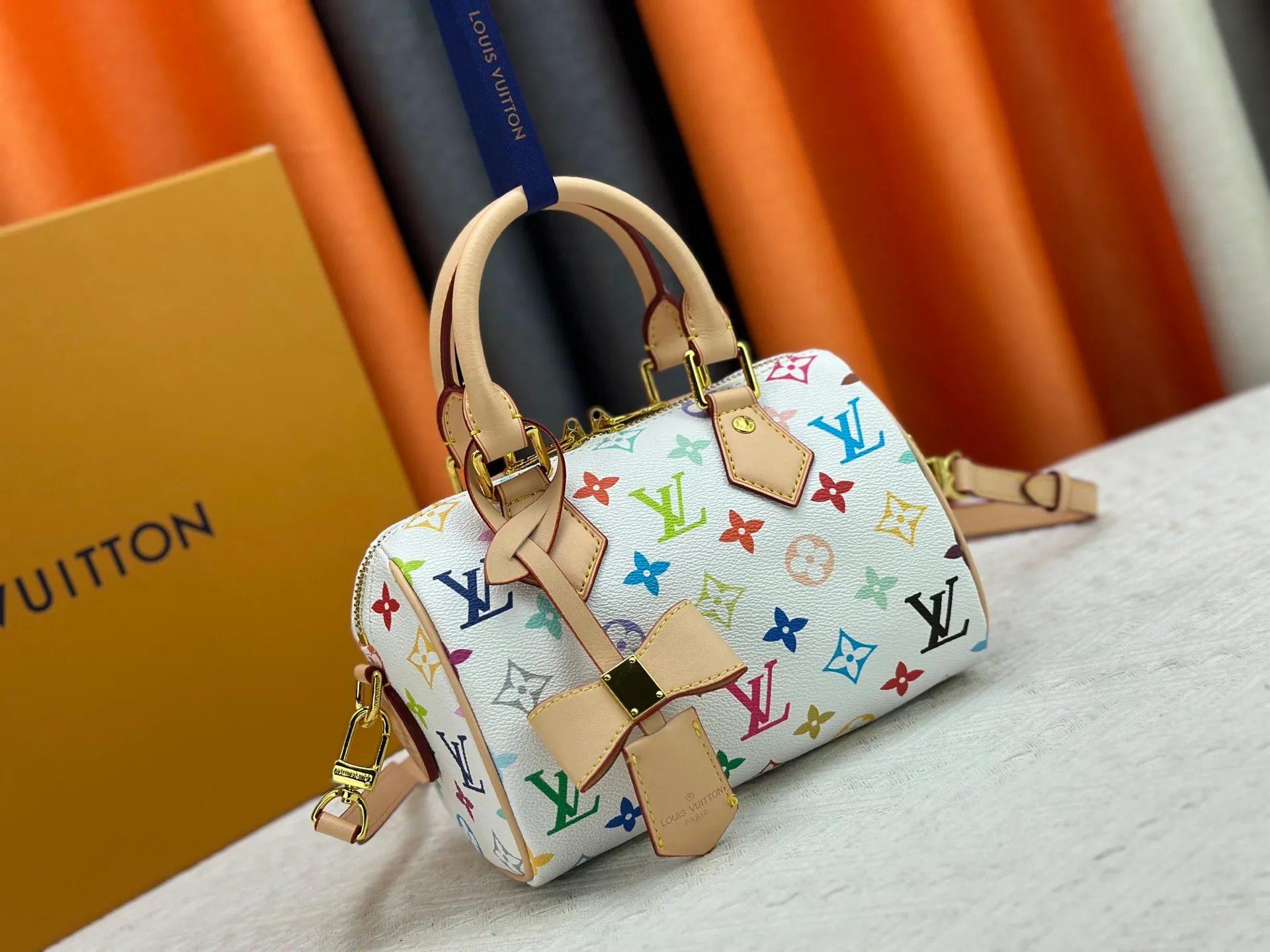 P260 Upgraded from the original version, this M46234 M46222 Speedy Bandoulière 20 handbag is made of soft coated canvas, with the full-length Monogram pattern traced in colorful rainbow tones, highlighting the smart style of the Louis Vuitton x Murakami reissue series. The Toron handle and detachable shoulder strap are constructed of cow leather, the metal corners recall classic luggage elements, and the bow-shaped key bag and padlock add brand touches. Dimensions: 20.5 x 13.5 x 12.0 cm (length x height x width)