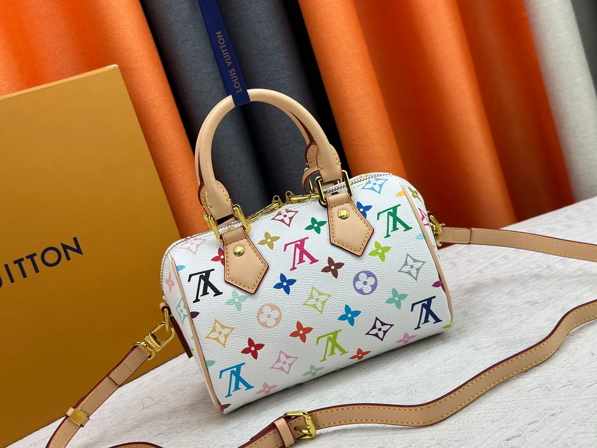 P260 Upgraded from the original version, this M46234 M46222 Speedy Bandoulière 20 handbag is made of soft coated canvas, with the full-length Monogram pattern traced in colorful rainbow tones, highlighting the smart style of the Louis Vuitton x Murakami reissue series. The Toron handle and detachable shoulder strap are constructed of cow leather, the metal corners recall classic luggage elements, and the bow-shaped key bag and padlock add brand touches. Dimensions: 20.5 x 13.5 x 12.0 cm (length x height x width)
