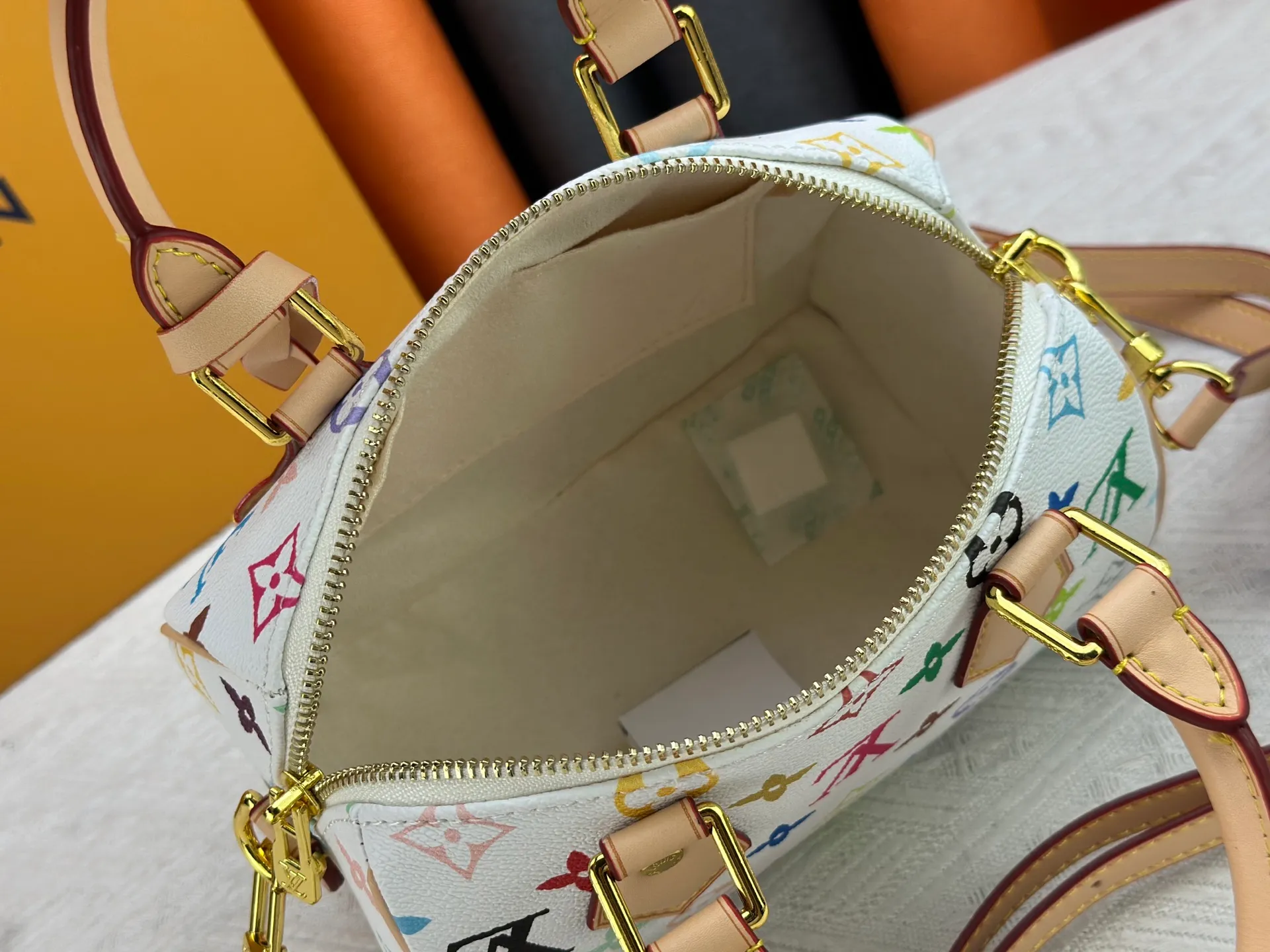 P260 Upgraded from the original version, this M46234 M46222 Speedy Bandoulière 20 handbag is made of soft coated canvas, with the full-length Monogram pattern traced in colorful rainbow tones, highlighting the smart style of the Louis Vuitton x Murakami reissue series. The Toron handle and detachable shoulder strap are constructed of cow leather, the metal corners recall classic luggage elements, and the bow-shaped key bag and padlock add brand touches. Dimensions: 20.5 x 13.5 x 12.0 cm (length x height x width)