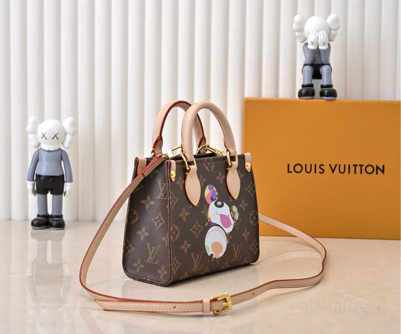 Batch 280💰M46993 M13668!🔥Lv&Takashi Murakami🐼Panda Print OnTheGo BB New Version The legendary ONTHEGO handbag: always able to meet your various needs for handbags. It has a large capacity but is not bulky. It is stiff and soft to the touch, making it suitable for home and travel. Tighten the side ties and it instantly transforms into a stylish urban handbag. Loosen the straps and it transforms into a chic and practical handbag. The slender leather handle can be carried over the shoulder or between the arms. The model shown here is made of Damier Azur canvas. Size: 18x15x8.5cm
