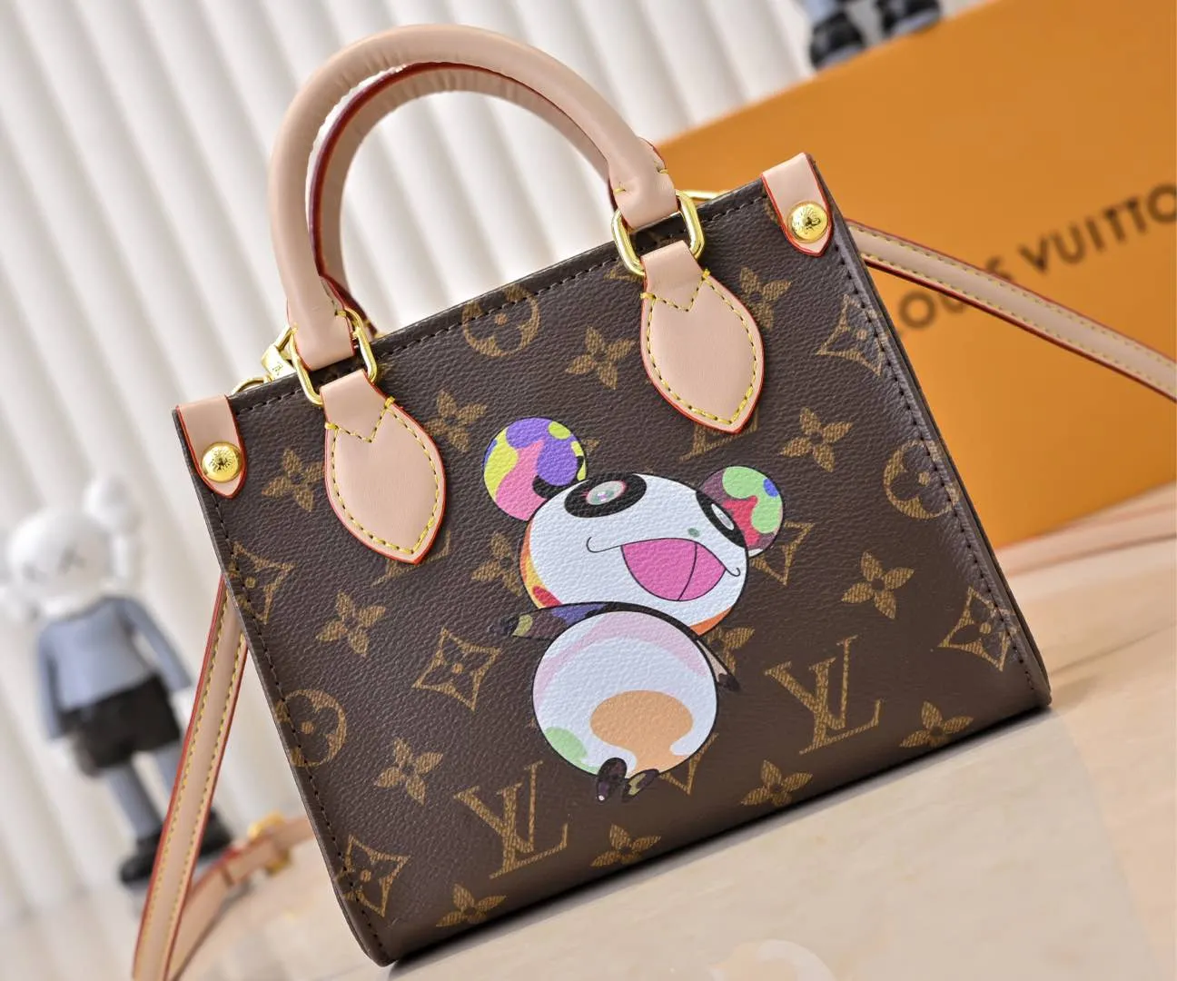 Batch 280💰M46993 M13668!🔥Lv&Takashi Murakami🐼Panda Print OnTheGo BB New Version The legendary ONTHEGO handbag: always able to meet your various needs for handbags. It has a large capacity but is not bulky. It is stiff and soft to the touch, making it suitable for home and travel. Tighten the side ties and it instantly transforms into a stylish urban handbag. Loosen the straps and it transforms into a chic and practical handbag. The slender leather handle can be carried over the shoulder or between the arms. The model shown here is made of Damier Azur canvas. Size: 18x15x8.5cm