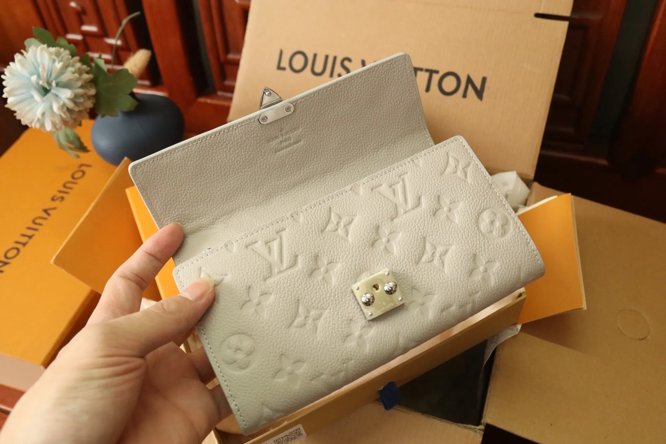 M13463 Gray 🌟 "Portefeuille Sara Metis" in P600 leather. The flaps are decorated with golden S-lock style buttons inspired by Louis Vuitton’s traditional trunks that symbolize “Métis”. It features an elegant rectangular shape and multiple pockets, as well as a spacious interior with compartments and card slots.  19 x 11 x 3cm
