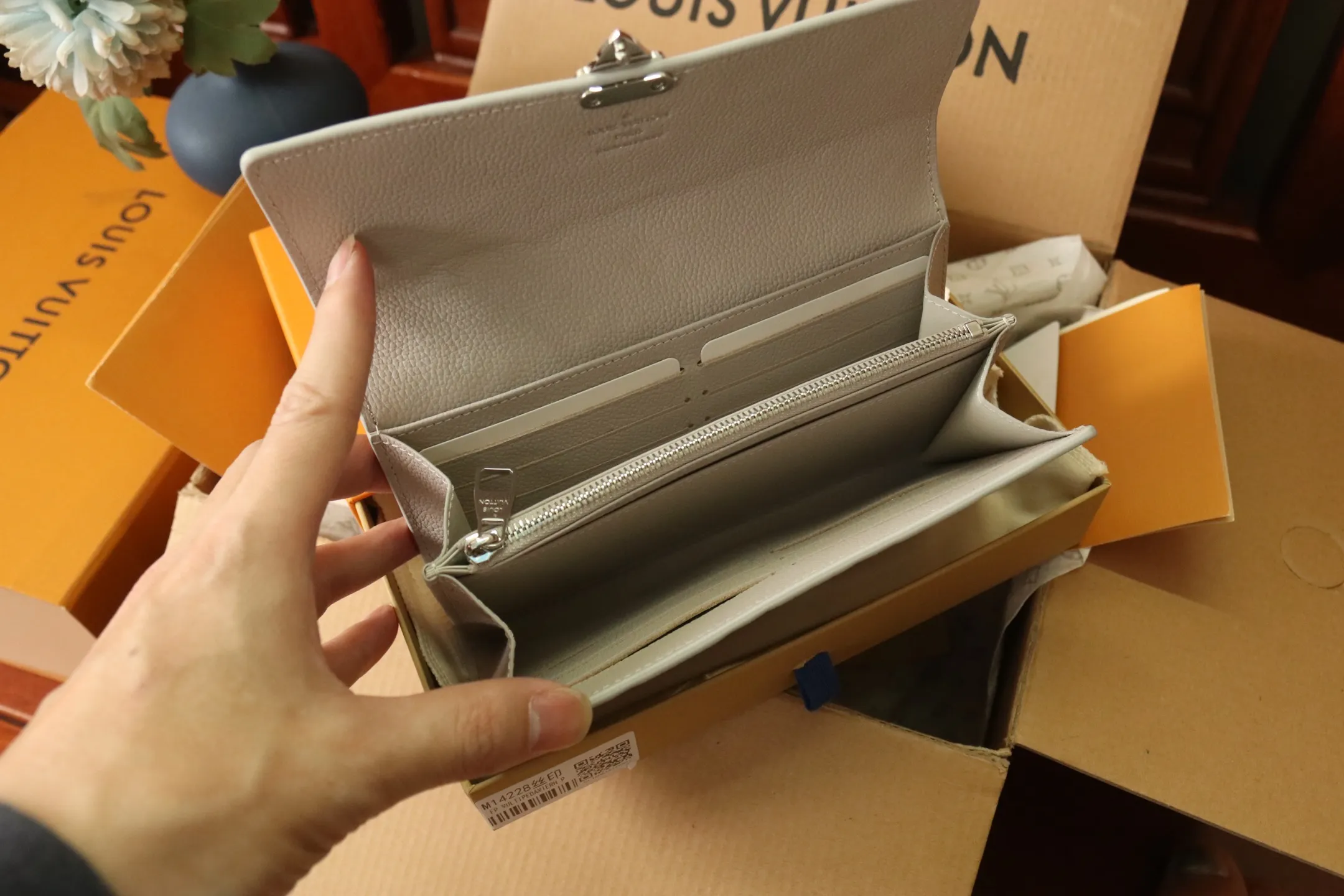 M13463 Gray 🌟 "Portefeuille Sara Metis" in P600 leather. The flaps are decorated with golden S-lock style buttons inspired by Louis Vuitton’s traditional trunks that symbolize “Métis”. It features an elegant rectangular shape and multiple pockets, as well as a spacious interior with compartments and card slots.  19 x 11 x 3cm