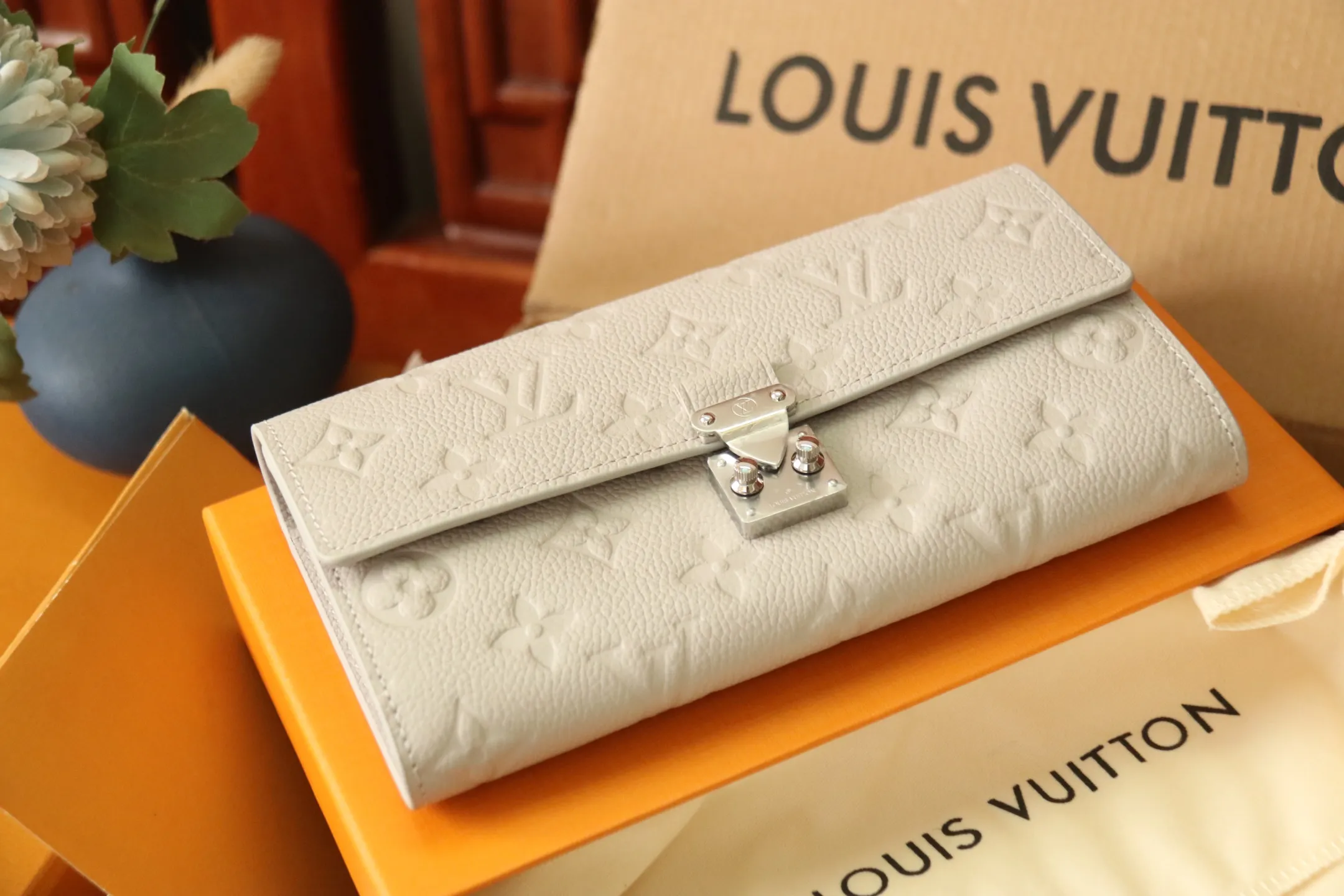 M13463 Gray 🌟 "Portefeuille Sara Metis" in P600 leather. The flaps are decorated with golden S-lock style buttons inspired by Louis Vuitton’s traditional trunks that symbolize “Métis”. It features an elegant rectangular shape and multiple pockets, as well as a spacious interior with compartments and card slots.  19 x 11 x 3cm