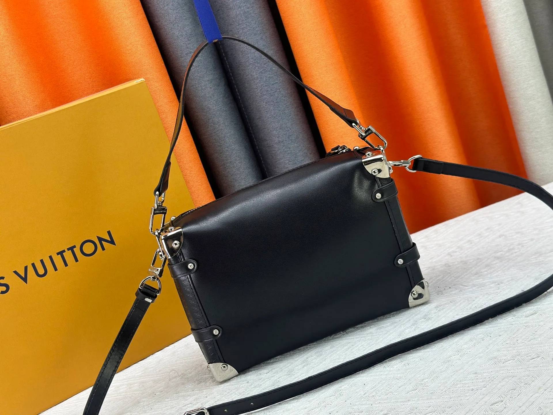 P300 M15195 M46358 This Side Trunk Vibe handbag reimagines the brand's classic Side Trunk silhouette with an avant-garde design, inspired by Louis Vuitton's traditional travel trunks. Crafted from smooth glossy Vibe textured cow leather, it features a leather-covered rivet frame and metal S-lock closure for a rock-and-roll style. Thanks to the multiple designs of the detachable chain, detachable leather handle and adjustable leather shoulder strap, it provides a variety of carrying options. Dimensions: 23.5x16x8.5cm