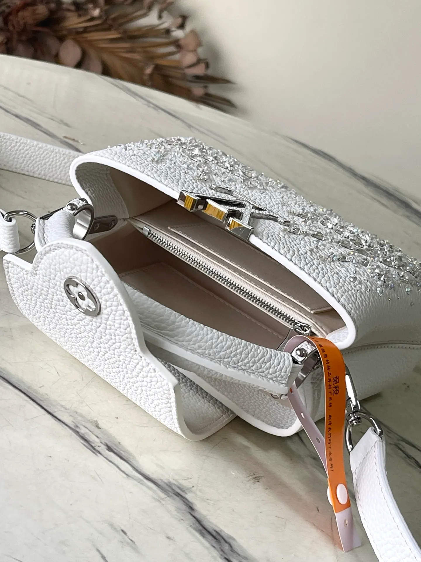 💰2700 "Special Grade Original Leather" M25934 White Mini As part of the "Extraordinary Series", this Capni mini bag has been redesigned with exquisite embroidery technology. It's made from calfskin and embellished with shimmering sequins in a romantic floral pattern and finished with gold-toned hardware. The backpack design provides a separated interior space and features the iconic LV initials as a tribute to the brand's exquisite craftsmanship. Dimensions: 21 x 13.6 x 8cm