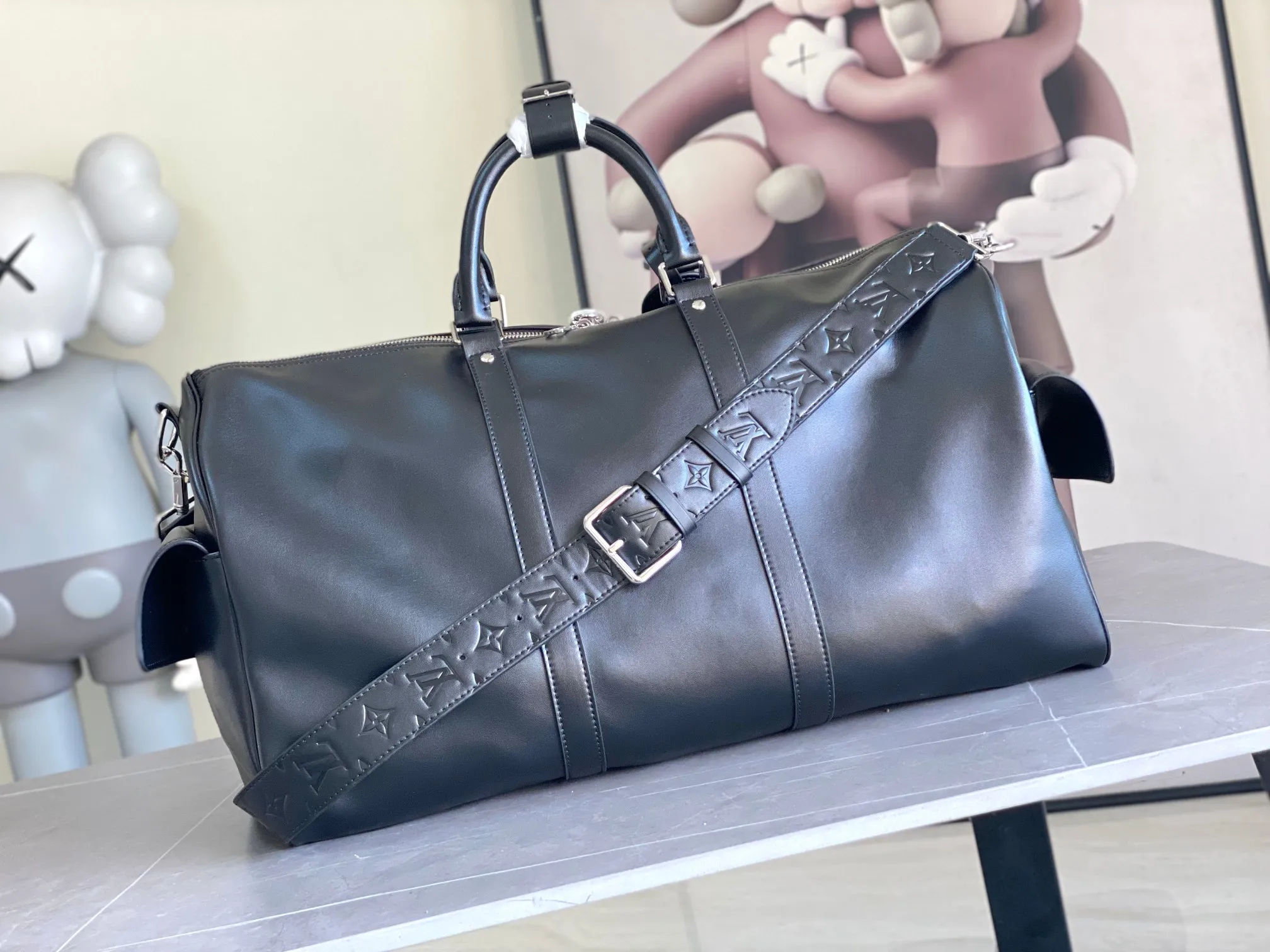 💰1760 (top layer leather) top original order M13992 This Keepall Bandoulière 50 travel bag depicts the Monogram pattern on the canvas surface and transforms into a cartoon image, making the Monogram flowers and LV letters present rich emotions of sadness or joy. The top handle and side straps are made of leather, continuing the consistent design of the Keepall series. Cartoon name tags can be customized. size：50x29x23cm