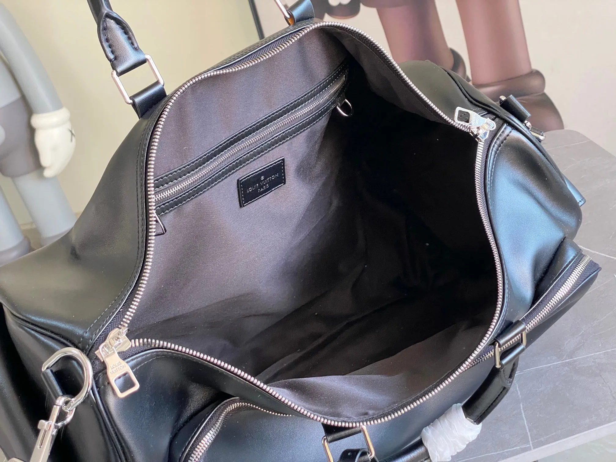 💰1760 (top layer leather) top original order M13992 This Keepall Bandoulière 50 travel bag depicts the Monogram pattern on the canvas surface and transforms into a cartoon image, making the Monogram flowers and LV letters present rich emotions of sadness or joy. The top handle and side straps are made of leather, continuing the consistent design of the Keepall series. Cartoon name tags can be customized. size：50x29x23cm