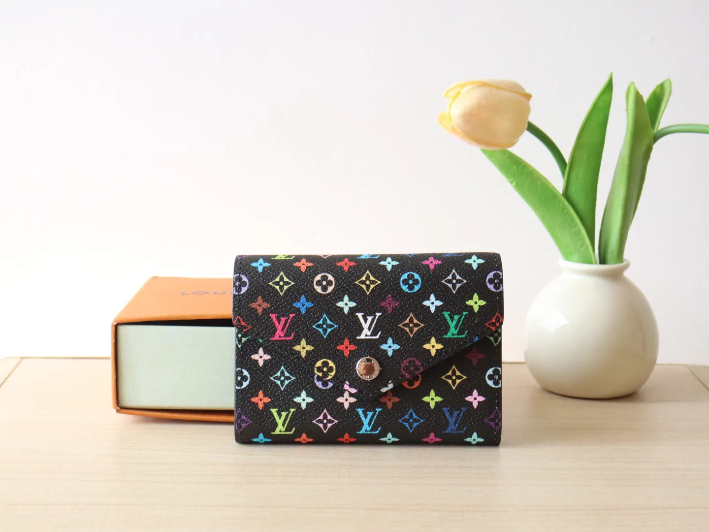 14163 Tri-Color Tri-fold Wallet🌟P90 This replica version of the Victorine wallet from the Louis Vuitton x Murakami series is small and exquisite. The colorful Monogram pattern reinterprets Louis Vuitton's classic logo with the famous rainbow tones of Japanese artist Takashi Murakami. The wallet is made of coated canvas with fine cowhide lining and silver-tone hardware. It has a zippered coin compartment and multiple interior compartments for banknotes and business cards. 12 x 9.5 x 2.5 cm (length x height x width)