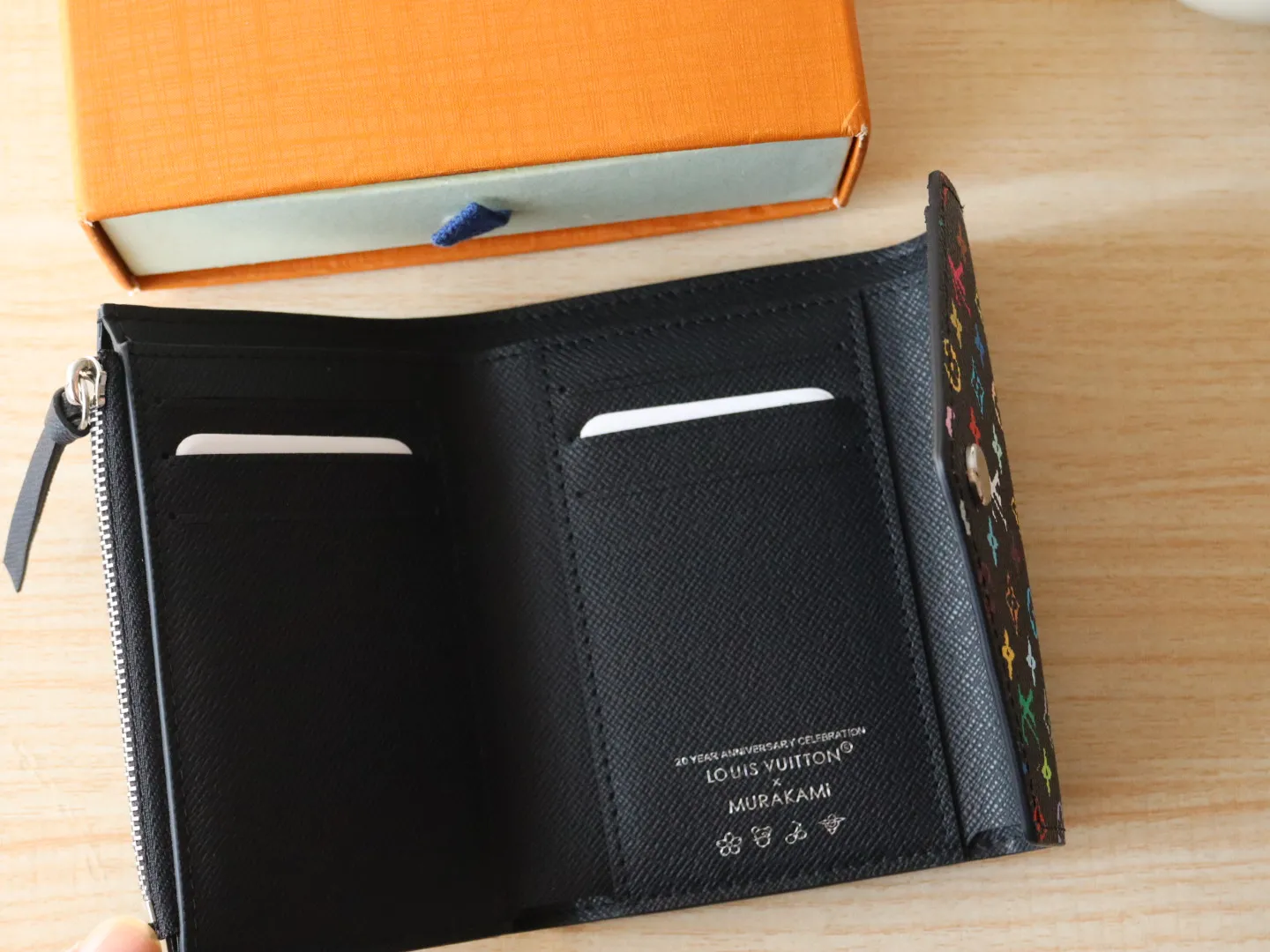 14163 Tri-Color Tri-fold Wallet🌟P90 This replica version of the Victorine wallet from the Louis Vuitton x Murakami series is small and exquisite. The colorful Monogram pattern reinterprets Louis Vuitton's classic logo with the famous rainbow tones of Japanese artist Takashi Murakami. The wallet is made of coated canvas with fine cowhide lining and silver-tone hardware. It has a zippered coin compartment and multiple interior compartments for banknotes and business cards. 12 x 9.5 x 2.5 cm (length x height x width)