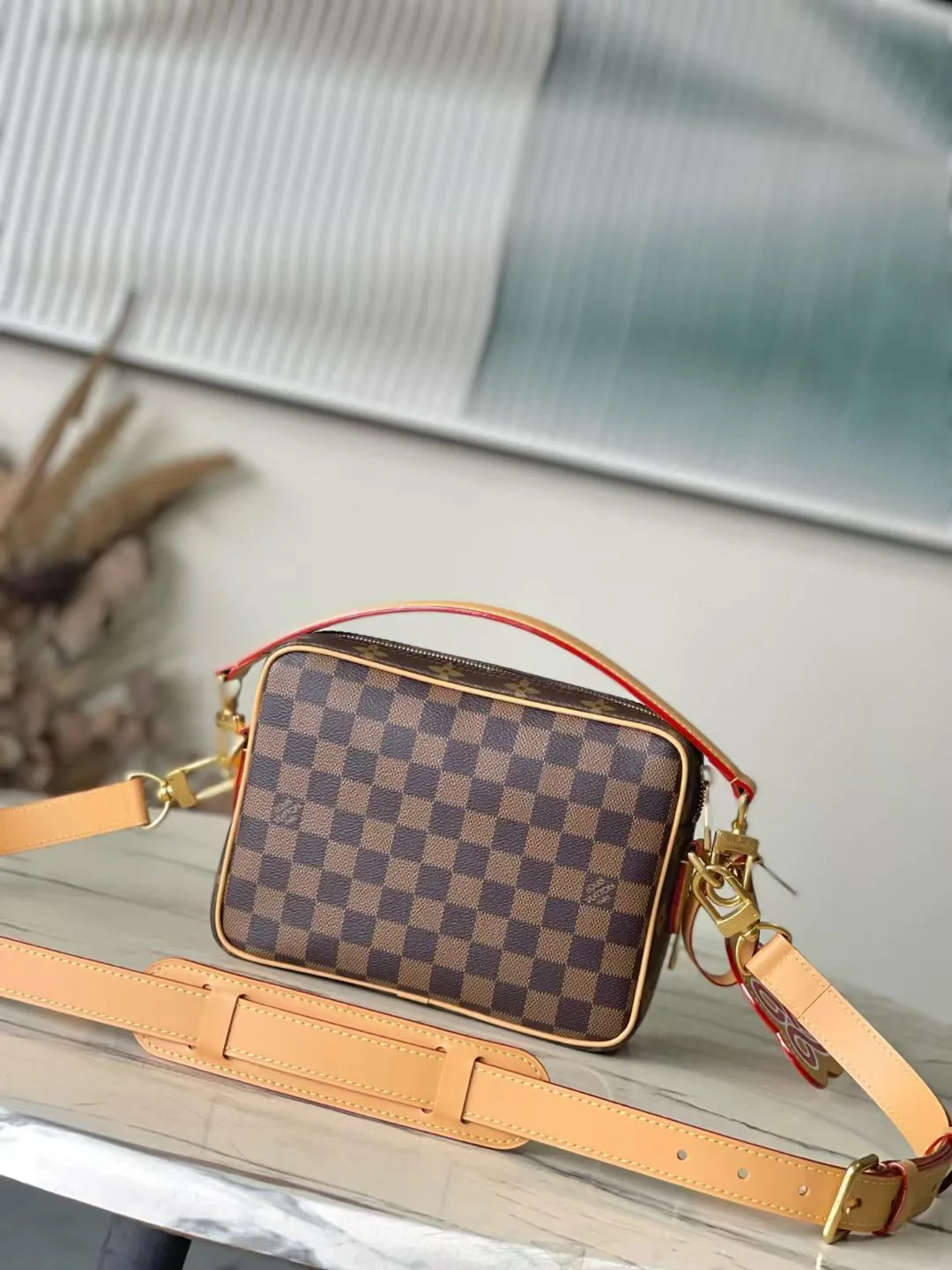 💰1280 Top Original M26068 This Nil crossbody bag is made of Monogram canvas body with Damier and Monogram Reverse canvas patches, creating an elegant collage effect. The spacious main compartment and zippered front pocket ensure easy access, while the removable top handle and shoulder strap allow for multiple carry options. 17.5 x 11 x 25 cm (height x width x length)