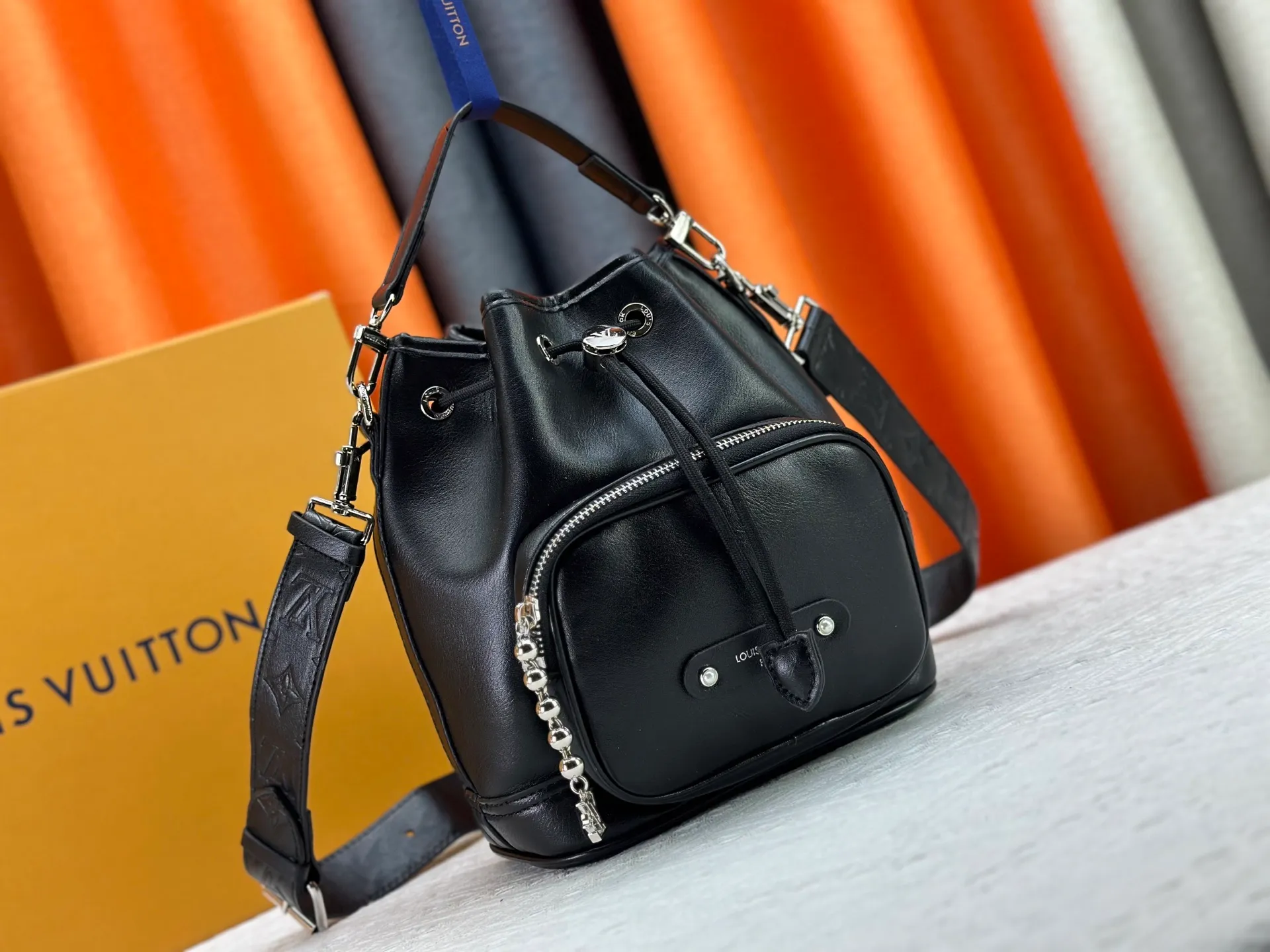 P280 Upgraded original version M13985 full leather black, official small size M14017 pure presbyopia Noe Cargo is a compact bucket bag, made of shiny cow leather, showing a nylon-like technological luster, and the lining is made of deep-toned fabric. Metal parts, including the LV letters attached to a ball chain, are the only color-coordinated elements on this monochromatic bag. Roomy front pocket inside. ·Cow leather trim fabric lined with hardware Drawstring and metal closure main compartment LV pendant zip puller ·Pearl rivets Louis Vuitton Paris patch ·Zip front pocket Shoulder strap: Removable, adjustable strap Half length: 40.0 cm Dimensions: 24✘22✘16cm (H✘L✘W)