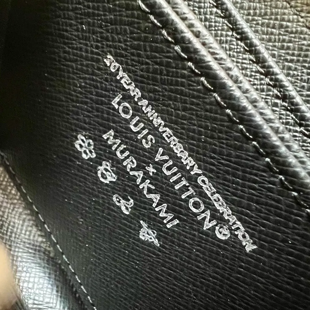 Factory Price 300 Top Original LV x TM Zippy Coin Purse M13409 Black Color (Three Colors - Murakami Takashi) As part of the Louis Vuitton x Murakami series reissue, the timeless Zippy coin purse is practical and playful, upgraded for this season. It's made from Monogram coated canvas in a cheerful rainbow of hues, in keeping with the Japanese artist's signature pop palette. The interior is secured with a silver zipper and is divided into multiple compartments for coins, banknotes and cards. Dimensions: 11 x 8.5 x 2 cm.