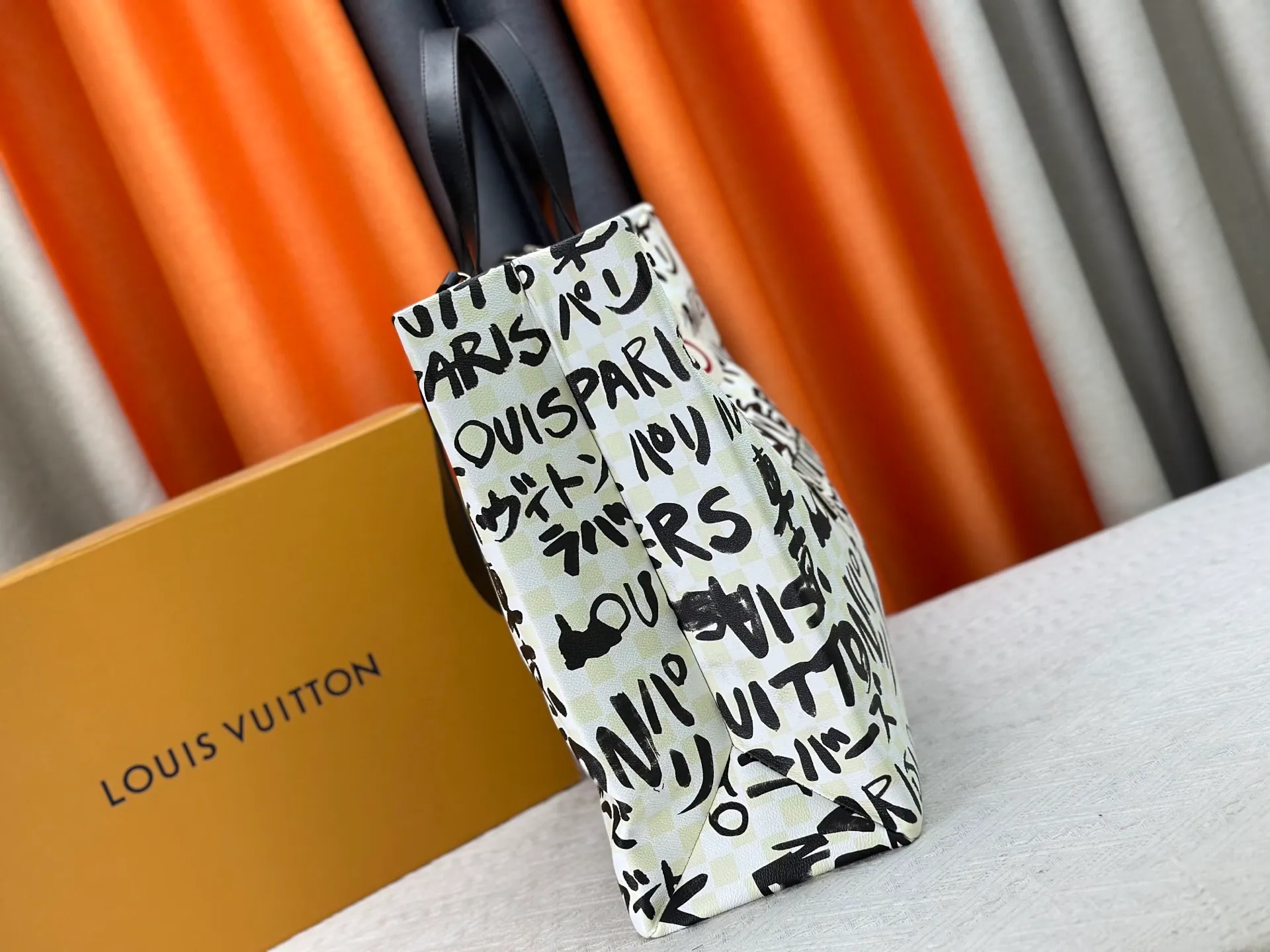 P300 M24457 M40797 This Shopper Tote medium handbag features Damier checkerboard pattern superimposed with eye-catching hand-painted elements, witnessing the joint creativity of Pharrell Williams and Japanese designer Nigo. The names Louis Vuitton, Paris and Tokyo, as well as the word Lvvers, are bilingual in French and Japanese, and the graphic cotton lining showcases Nigo's signature style. Size: 41x34x16cm