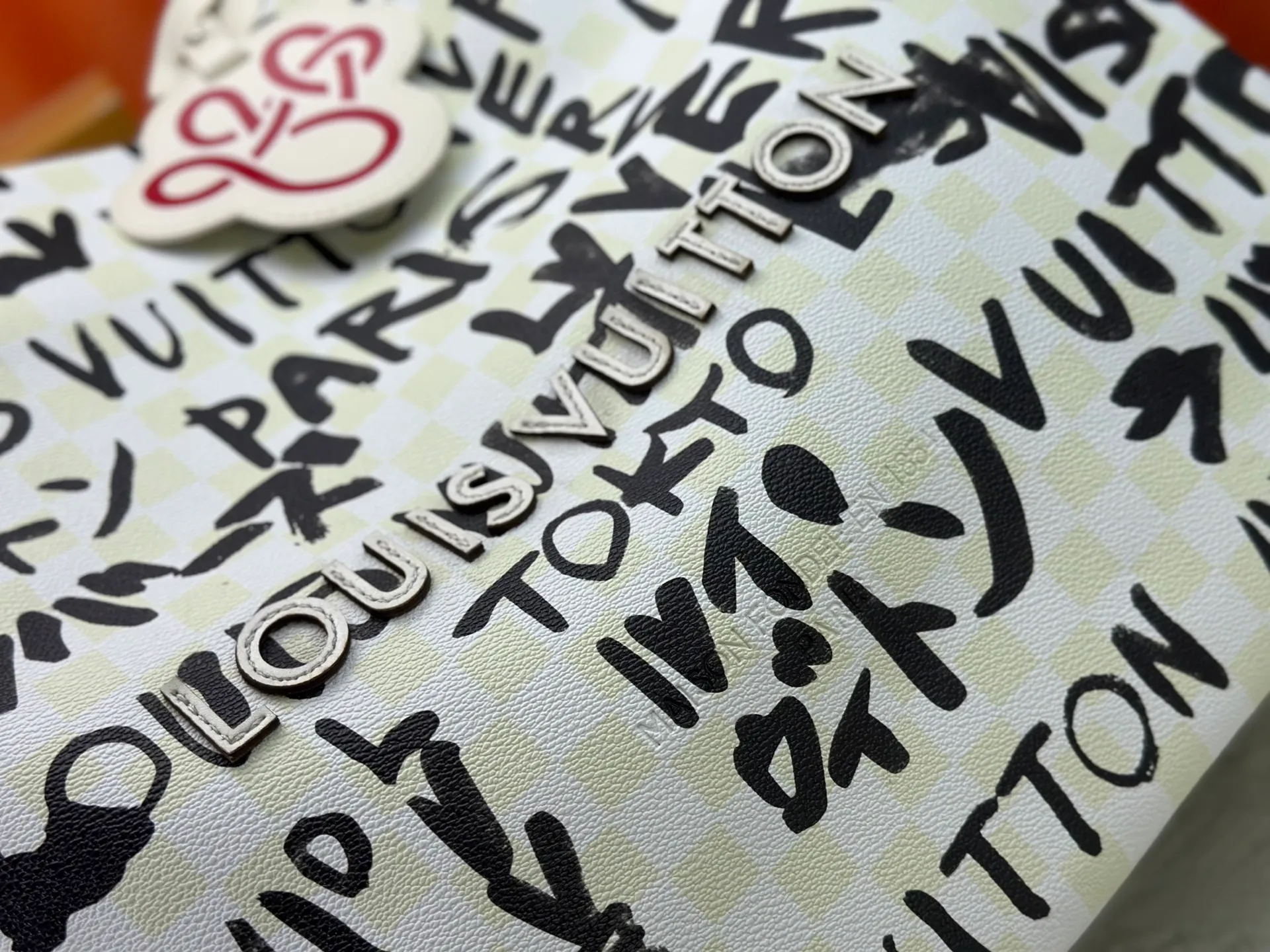 P300 M24457 M40797 This Shopper Tote medium handbag features Damier checkerboard pattern superimposed with eye-catching hand-painted elements, witnessing the joint creativity of Pharrell Williams and Japanese designer Nigo. The names Louis Vuitton, Paris and Tokyo, as well as the word Lvvers, are bilingual in French and Japanese, and the graphic cotton lining showcases Nigo's signature style. Size: 41x34x16cm