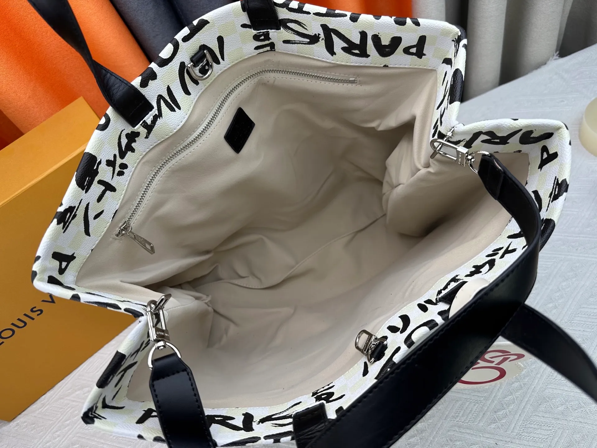 P300 M24457 M40797 This Shopper Tote medium handbag features Damier checkerboard pattern superimposed with eye-catching hand-painted elements, witnessing the joint creativity of Pharrell Williams and Japanese designer Nigo. The names Louis Vuitton, Paris and Tokyo, as well as the word Lvvers, are bilingual in French and Japanese, and the graphic cotton lining showcases Nigo's signature style. Size: 41x34x16cm