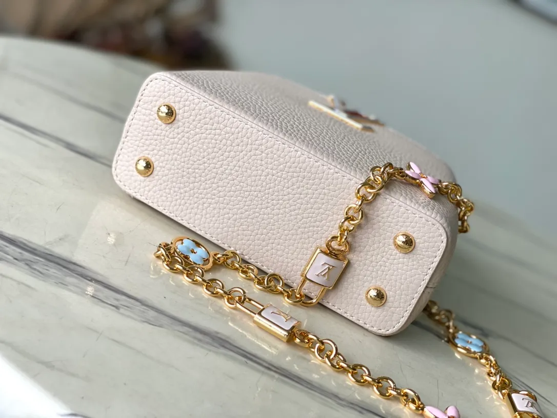 💰2200 (Special grade original leather) M23952 mini This Capucines mini handbag comes from the Lovelock Chain series. The Taurillon leather bag has a dotted rope that looks like a jewelry chain, with a padlock and pastel enamel Monogram flowers, echoing the dual tones of the leather. The detachable chain and top handle provide more carrying options, and the inner pocket is equipped with a small mirror for easy touch-ups at any time. Dimensions: 21 × 14 × 8 cm