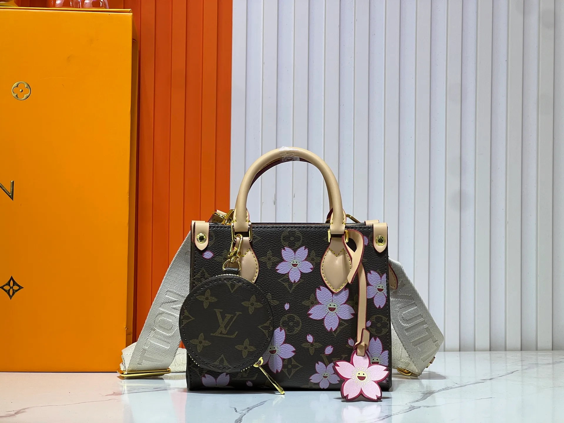 Batch 300💰M45659 M46373🔥Lv&Takashi Murakami🐼Sakura🌸OnTheGo small new version The legendary ONTHEGO handbag: always able to meet your various needs for handbags. It has a large capacity but is not bulky. It is stiff and soft to the touch, making it suitable for home and travel. Tighten the side ties and it instantly transforms into a stylish urban handbag. Loosen the straps and it transforms into a chic and practical handbag. The slender leather handle can be carried over the shoulder or between the arms. The model shown here is made of Damier Azur canvas. Size: 18x15x8.5cm