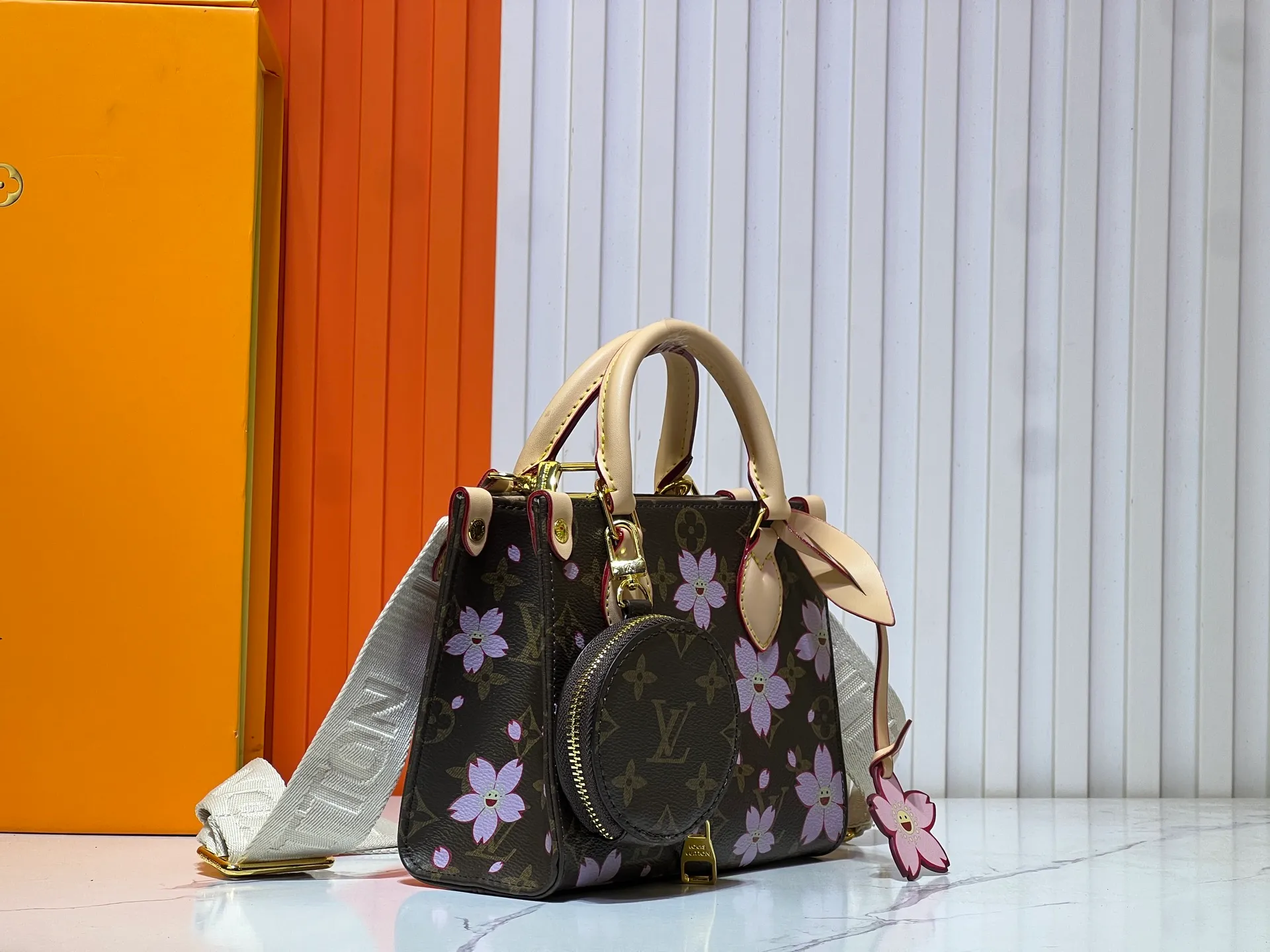 Batch 300💰M45659 M46373🔥Lv&Takashi Murakami🐼Sakura🌸OnTheGo small new version The legendary ONTHEGO handbag: always able to meet your various needs for handbags. It has a large capacity but is not bulky. It is stiff and soft to the touch, making it suitable for home and travel. Tighten the side ties and it instantly transforms into a stylish urban handbag. Loosen the straps and it transforms into a chic and practical handbag. The slender leather handle can be carried over the shoulder or between the arms. The model shown here is made of Damier Azur canvas. Size: 18x15x8.5cm