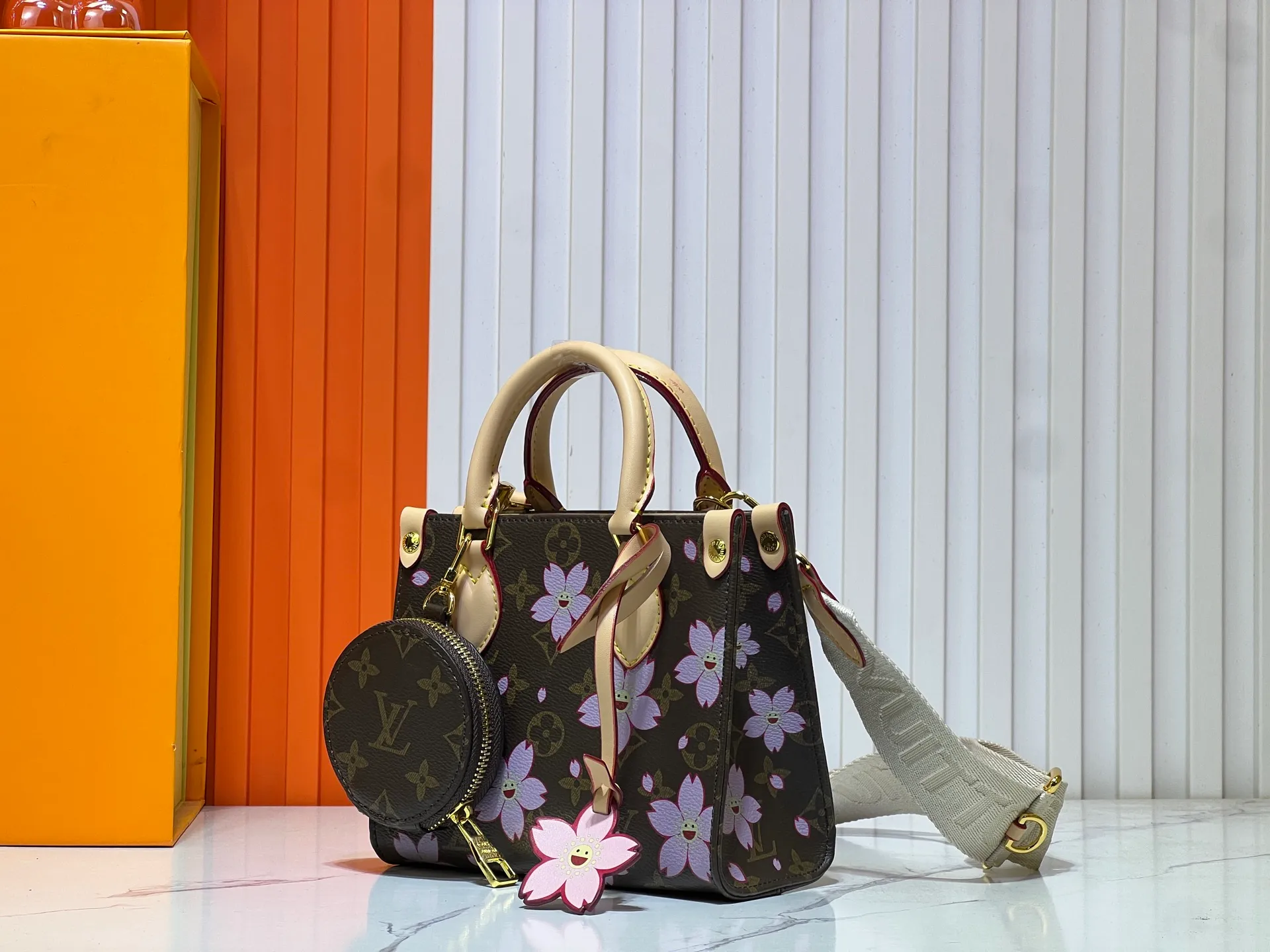 Batch 300💰M45659 M46373🔥Lv&Takashi Murakami🐼Sakura🌸OnTheGo small new version The legendary ONTHEGO handbag: always able to meet your various needs for handbags. It has a large capacity but is not bulky. It is stiff and soft to the touch, making it suitable for home and travel. Tighten the side ties and it instantly transforms into a stylish urban handbag. Loosen the straps and it transforms into a chic and practical handbag. The slender leather handle can be carried over the shoulder or between the arms. The model shown here is made of Damier Azur canvas. Size: 18x15x8.5cm