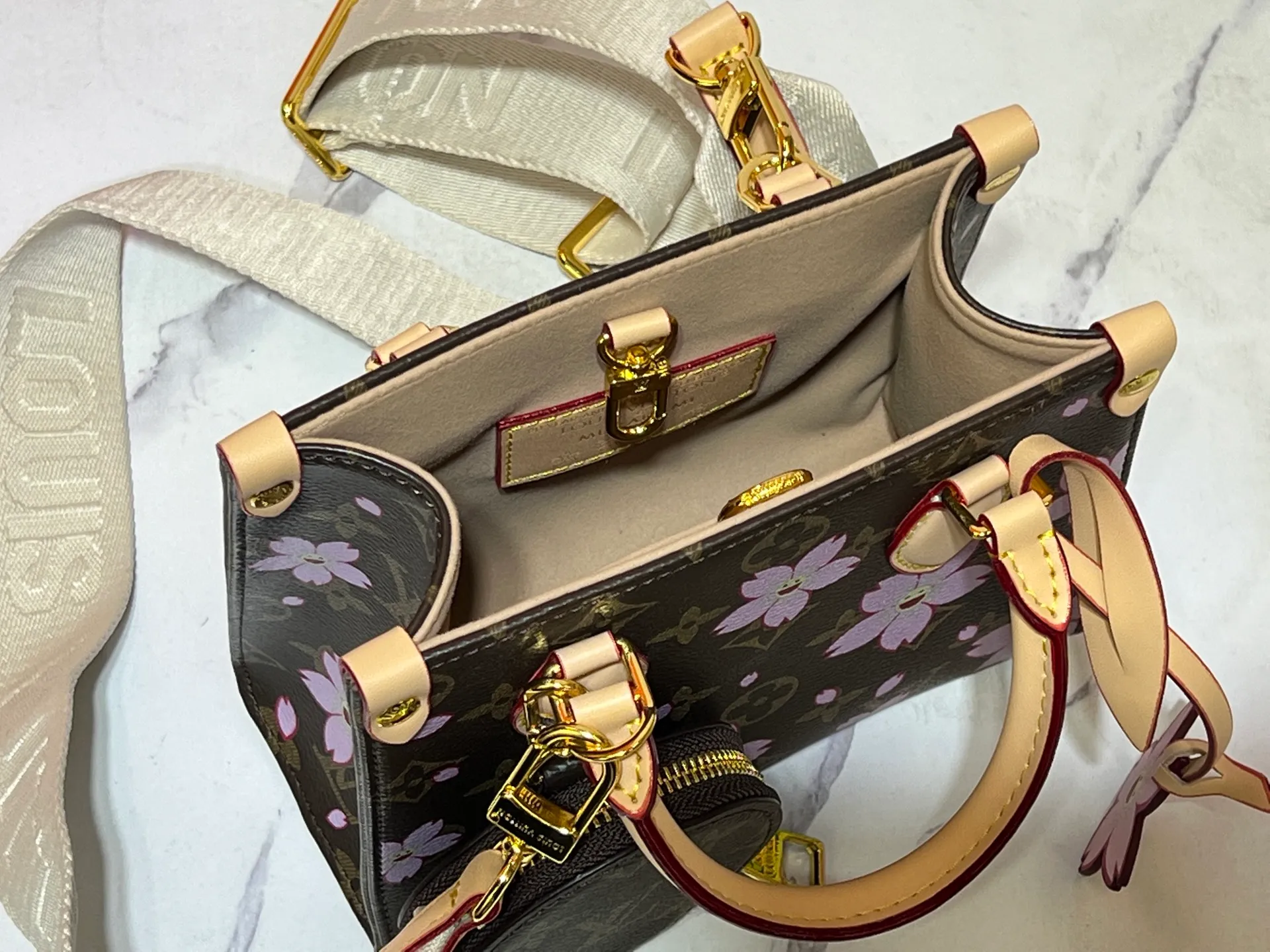 Batch 300💰M45659 M46373🔥Lv&Takashi Murakami🐼Sakura🌸OnTheGo small new version The legendary ONTHEGO handbag: always able to meet your various needs for handbags. It has a large capacity but is not bulky. It is stiff and soft to the touch, making it suitable for home and travel. Tighten the side ties and it instantly transforms into a stylish urban handbag. Loosen the straps and it transforms into a chic and practical handbag. The slender leather handle can be carried over the shoulder or between the arms. The model shown here is made of Damier Azur canvas. Size: 18x15x8.5cm