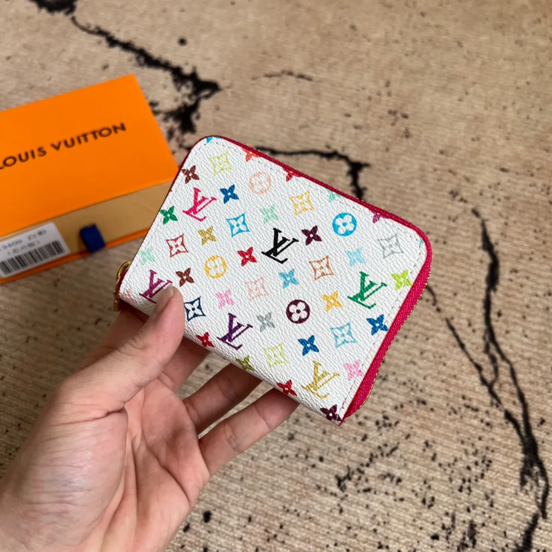 Factory Price 300 Top Original LV x TM Zippy Coin Purse M13409 White Color (Three Colors-Takashi Murakami) As part of the Louis Vuitton x Murakami series reissue, the timeless Zippy coin purse is practical and playful, upgraded for this season. It's made from Monogram coated canvas in a cheerful rainbow of hues, in keeping with the Japanese artist's signature pop palette. The interior is secured with a silver zipper and is divided into multiple compartments for coins, banknotes and cards. Dimensions: 11 x 8.5 x 2 cm.