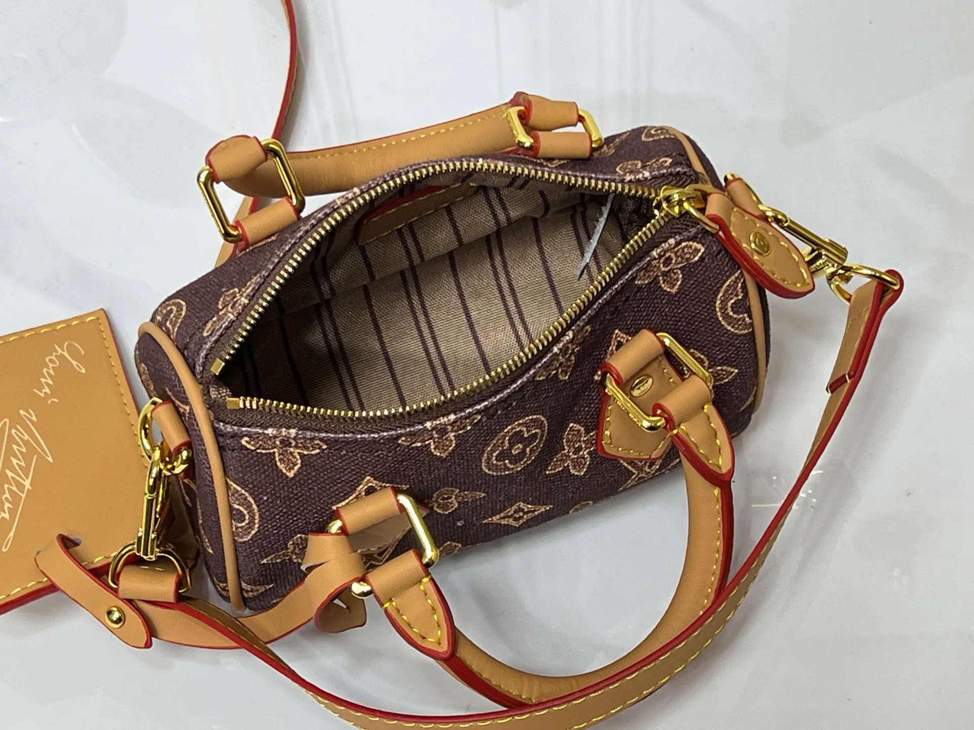 Batch 240💰M28322 Red M28323 M27610 M81085 [Exclusive background shot] This Nano Speedy handbag condenses the configuration of Louis Vuitton's classic Speedy handbag. It is made of Monogram canvas with distressed cow leather details and dazzling metal parts, making it easy to carry with you for daily needs. The handles and removable and adjustable shoulder strap allow for a variety of styling possibilities. 16.0 x 10.0 x 7.5 cm (L x H x W) • Monogram coated canvas • Cow leather trim • Metal hardware • Zipper closure • Space to store daily necessities such as a 6.1-inch smartphone, card holder and lipstick • Shoulder strap: removable, adjustable • Half-length strap: 45.5 cm • Half-length strap adjustable to: 54.0 cm • Handle: Double handle