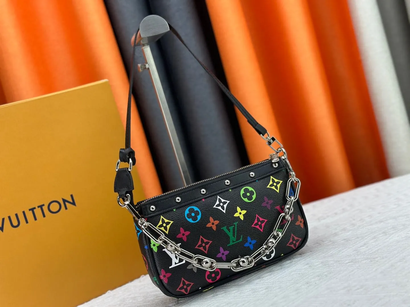 P220 M13404 M13663 Black color White color This Pochette Accessoires handbag is made of coated canvas, with colorful Monogram patterns to interpret the smart style of the Louis Vuitton × Murakami cross-border collaboration series. Calf leather trim and dazzling hardware add to the sophisticated details, while the detachable shoulder strap and chain provide flexible carry. Size: 22x13x4cm