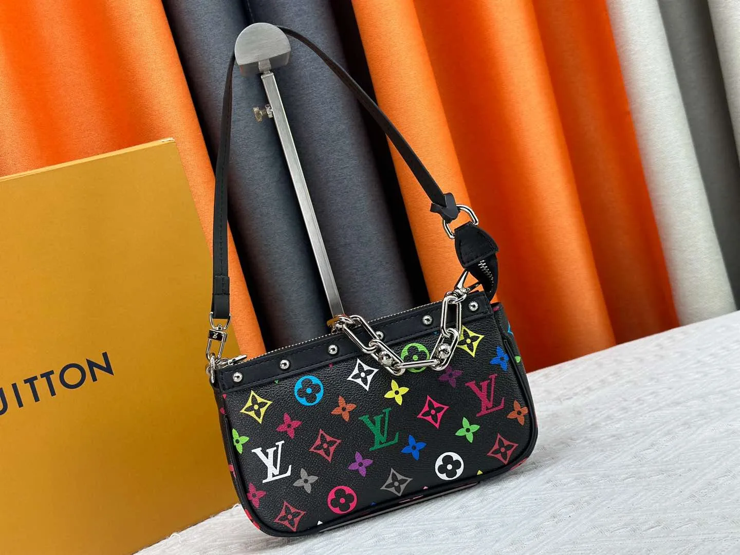 P220 M13404 M13663 Black color White color This Pochette Accessoires handbag is made of coated canvas, with colorful Monogram patterns to interpret the smart style of the Louis Vuitton × Murakami cross-border collaboration series. Calf leather trim and dazzling hardware add to the sophisticated details, while the detachable shoulder strap and chain provide flexible carry. Size: 22x13x4cm