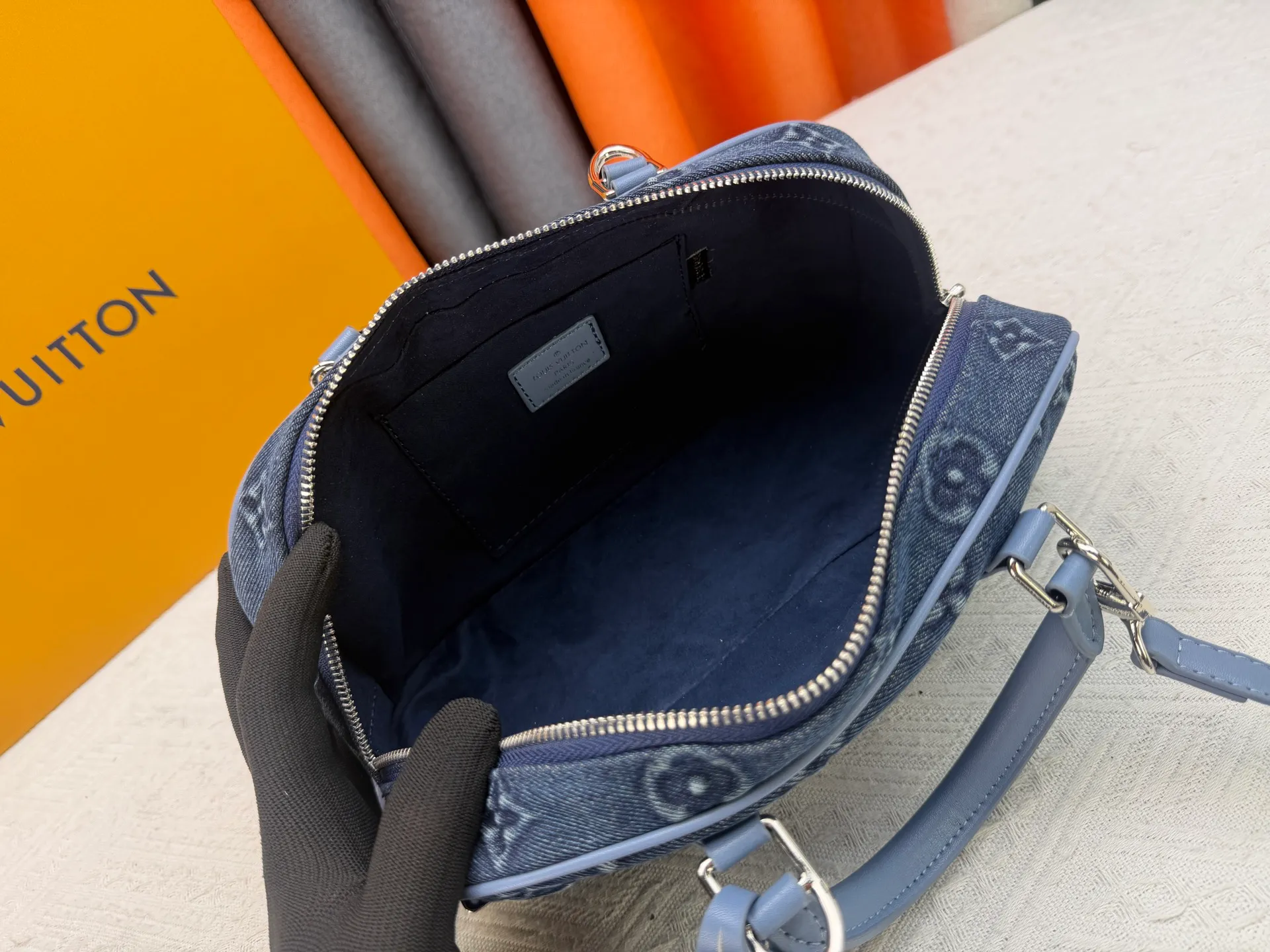 P360 M13084 Embossed Denim This Handbag East West handbag is from the Louis Vuitton x Takashi Murakami reissue series, using the artist's signature rainbow tones to trace the full-length Monogram pattern. Sleek horizontal construction lines the top handle, studded side straps, detachable and adjustable shoulder strap and LV x TM key holder, with cowhide leather details and sophisticated corners that nod to the brand's traditional luggage.  14 x 10 x 27 cm (H x W x L) Monogram coated canvas Cow leather trim Textile lining Metal hardware Zip closure Internal pocket Holds smartphone, keys, headphones and Zippy wallet Shoulder strap: removable, not adjustable Strap half-length: 44.0 cm Handle: Double handle